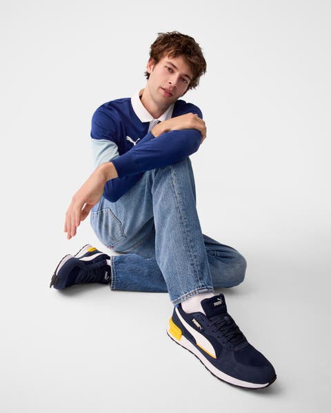 A man wearing a polo shirt and jeans with sneakers.