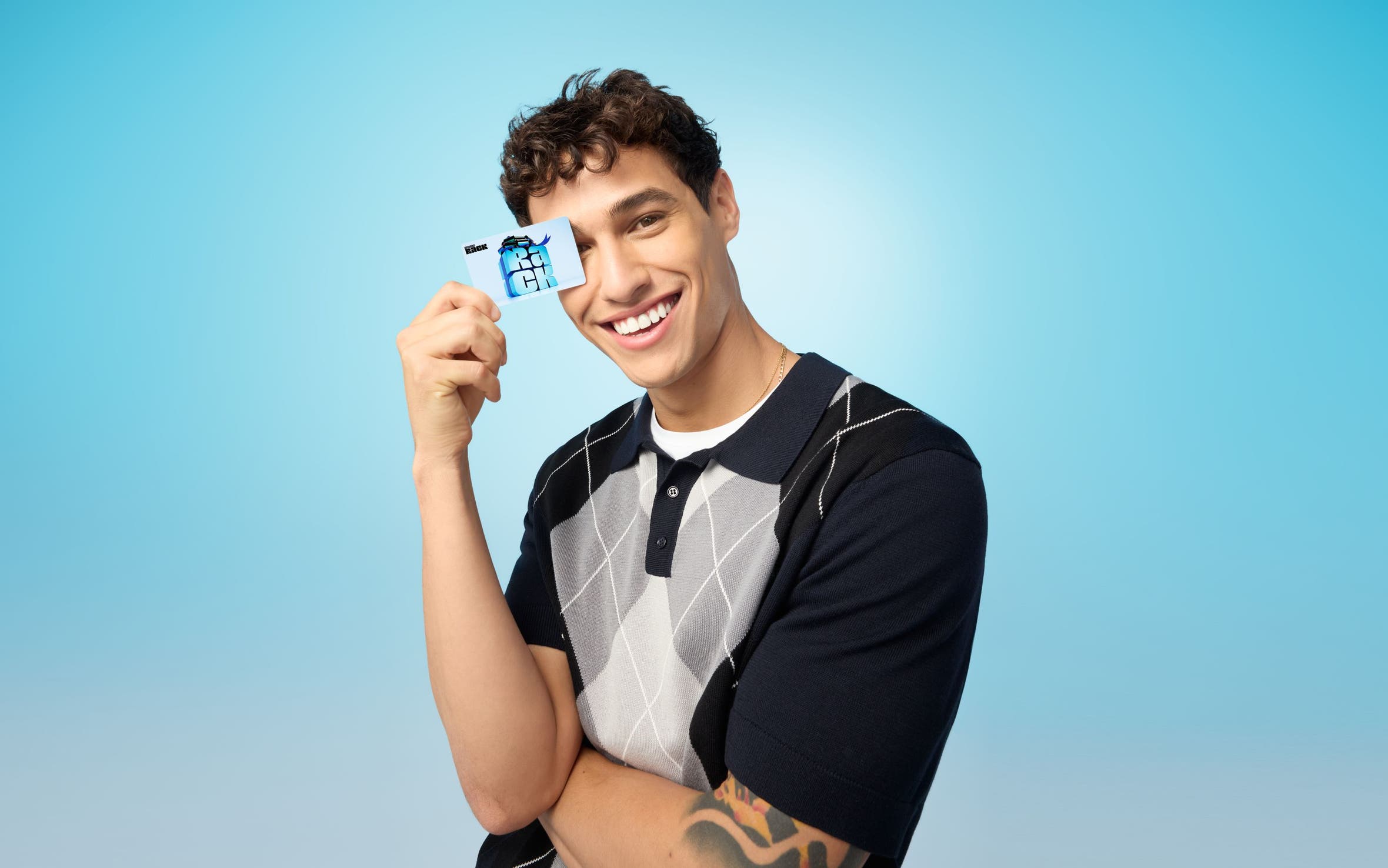 A man in an argyle sweater holding a gift card.