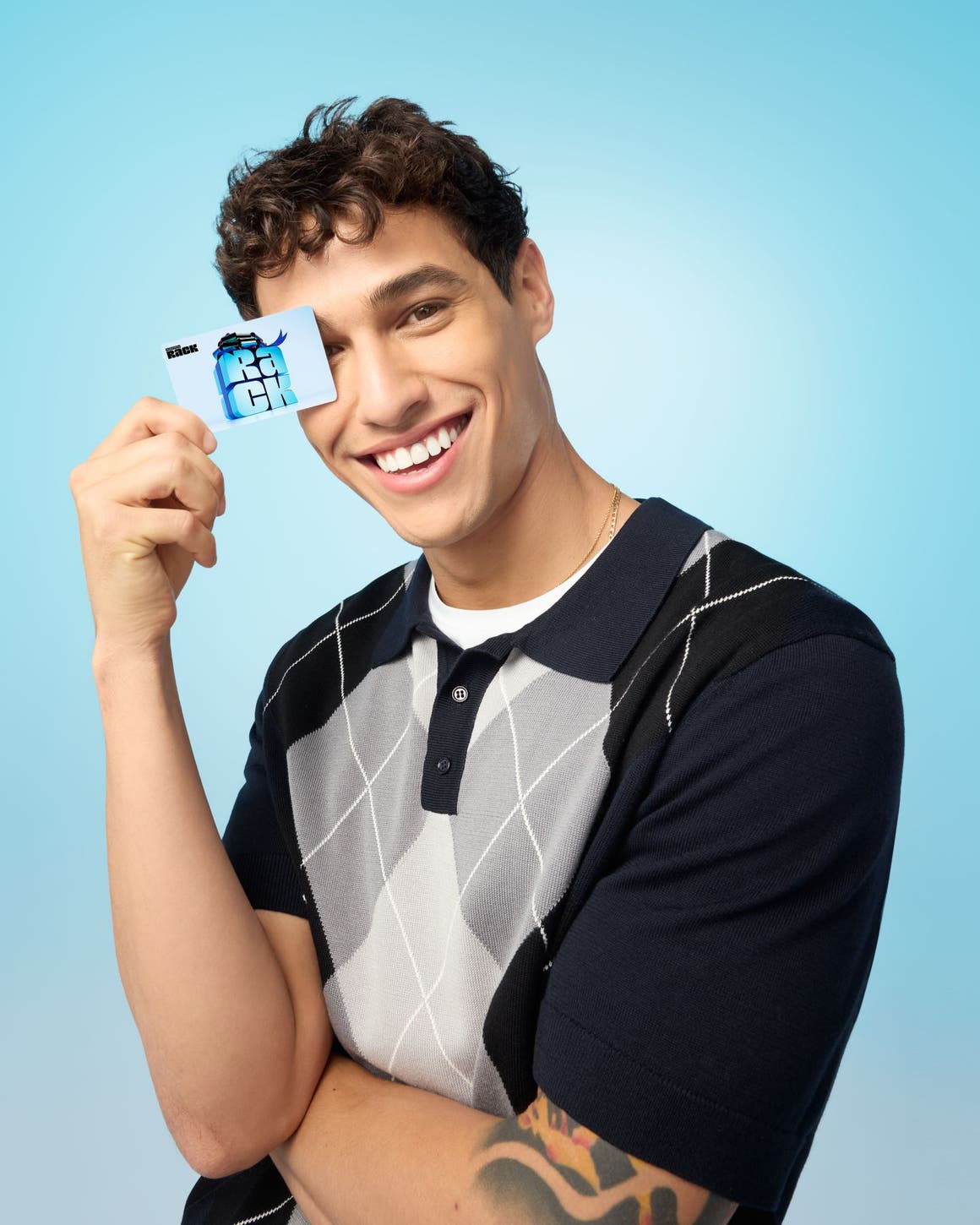 A man in an argyle sweater holding a gift card.