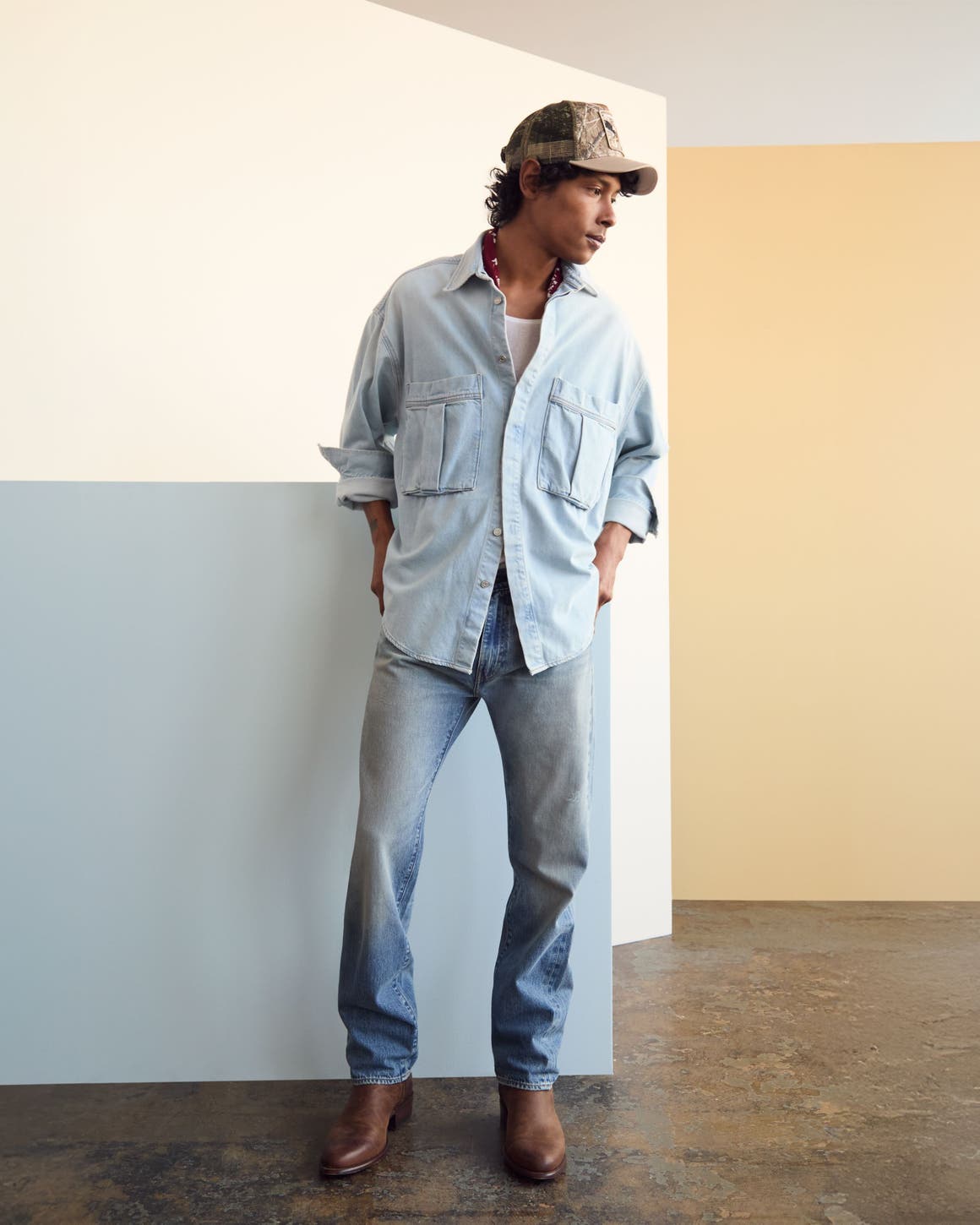 Man wearing a denim shirt and jeans with a baseball cap and boots.
