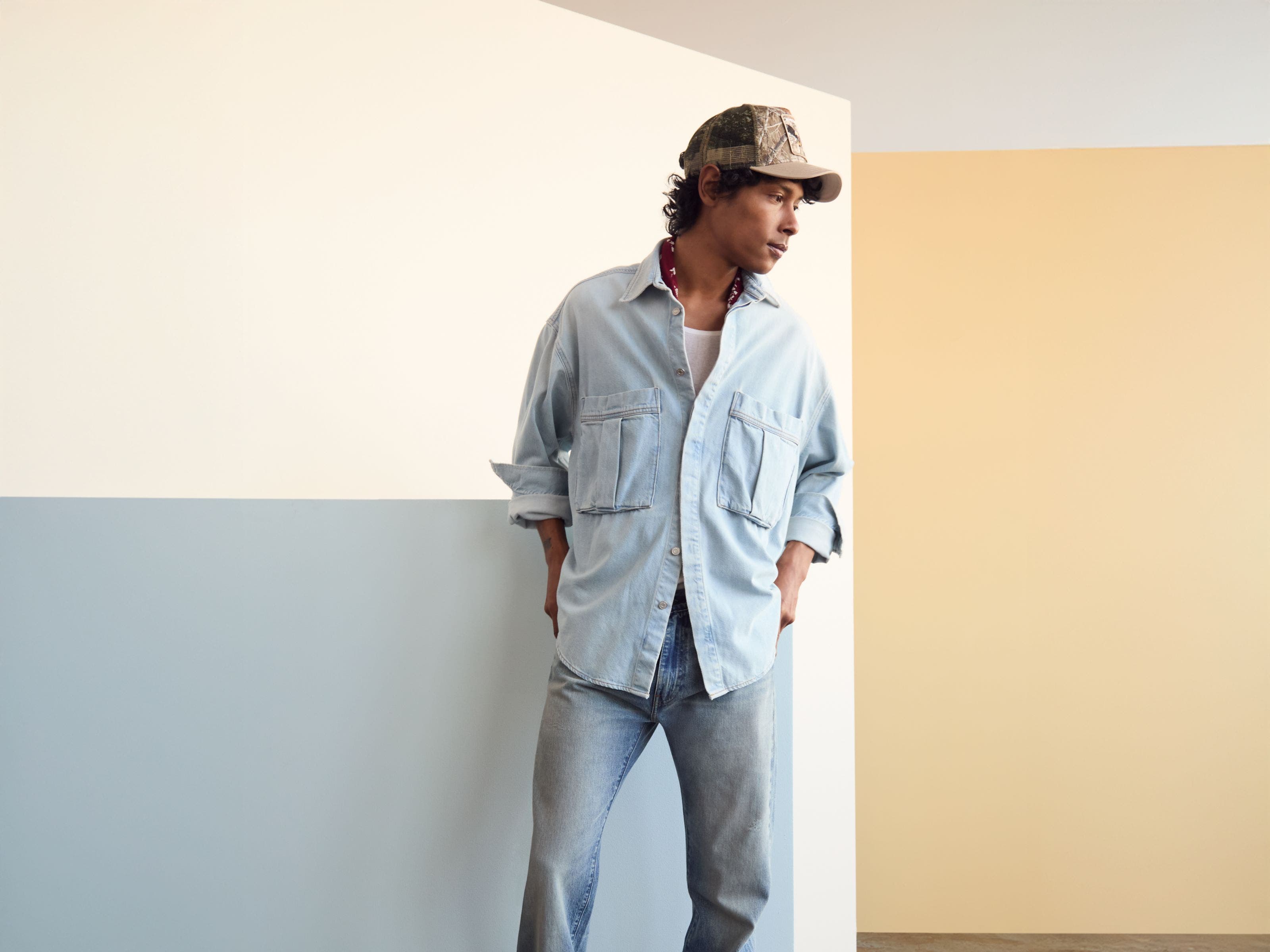 Man wearing a denim shirt and jeans with a baseball cap and boots.