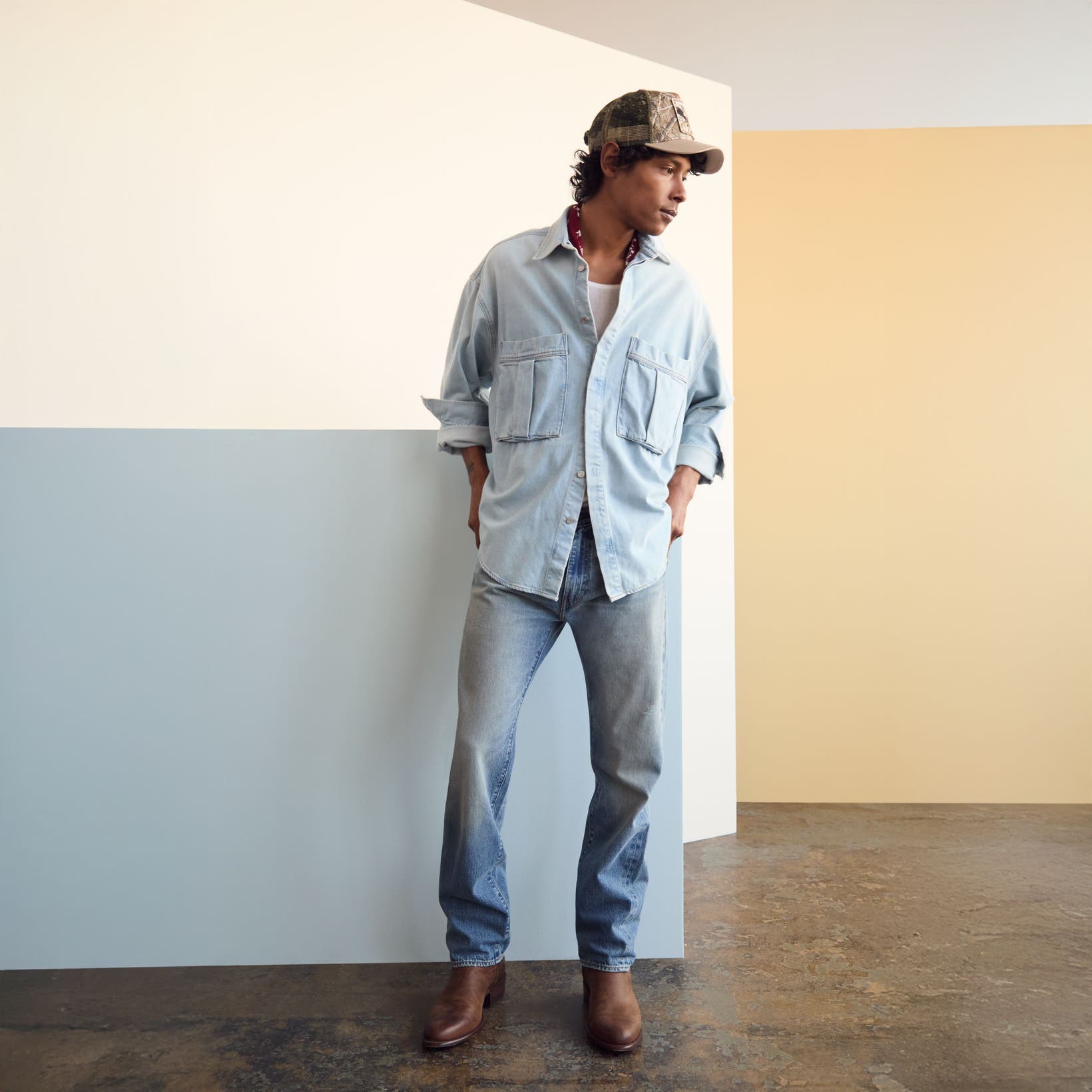Man wearing a denim shirt and jeans with a baseball cap and boots.