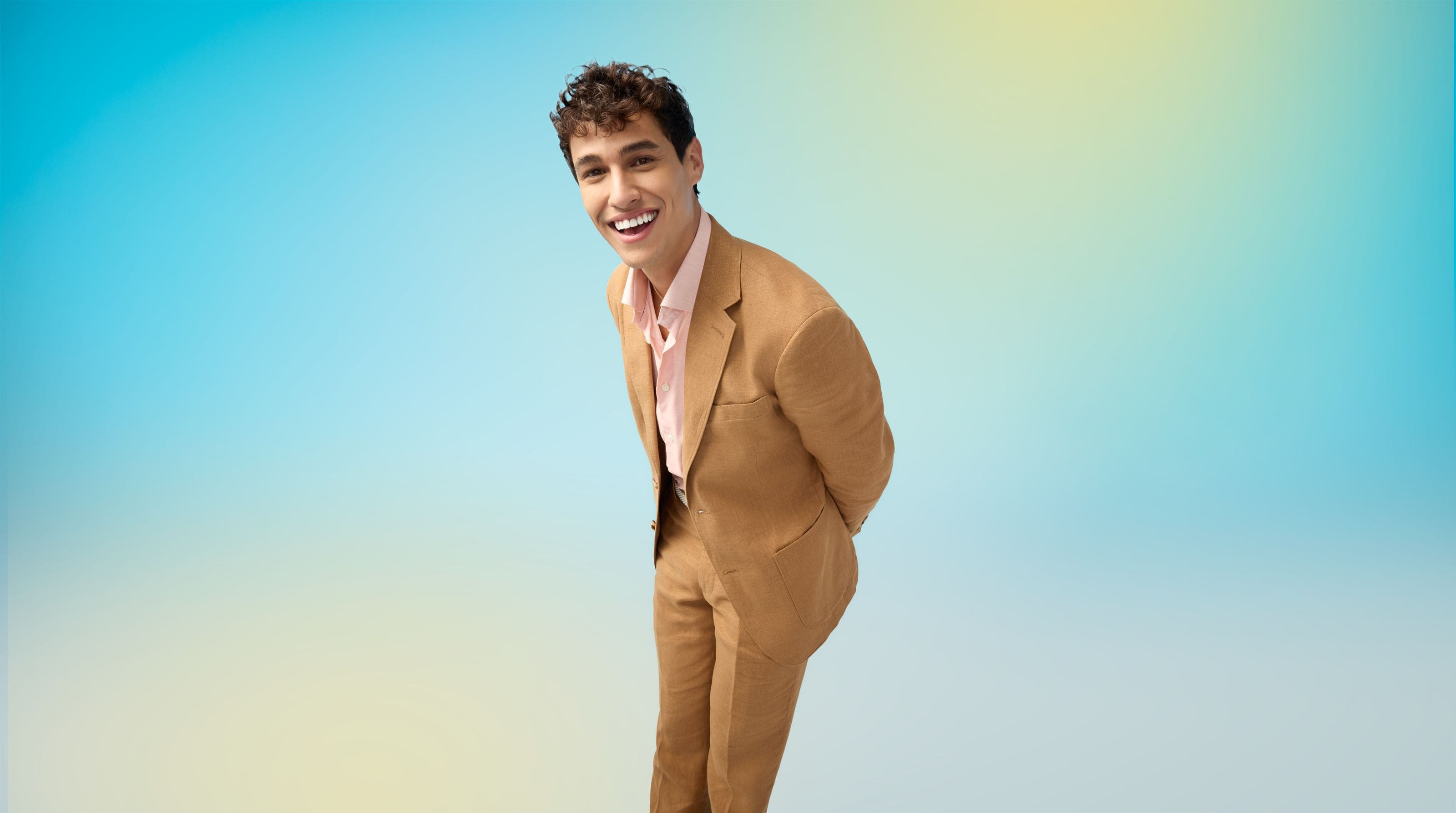 A man in a tan suit and pink shirt.