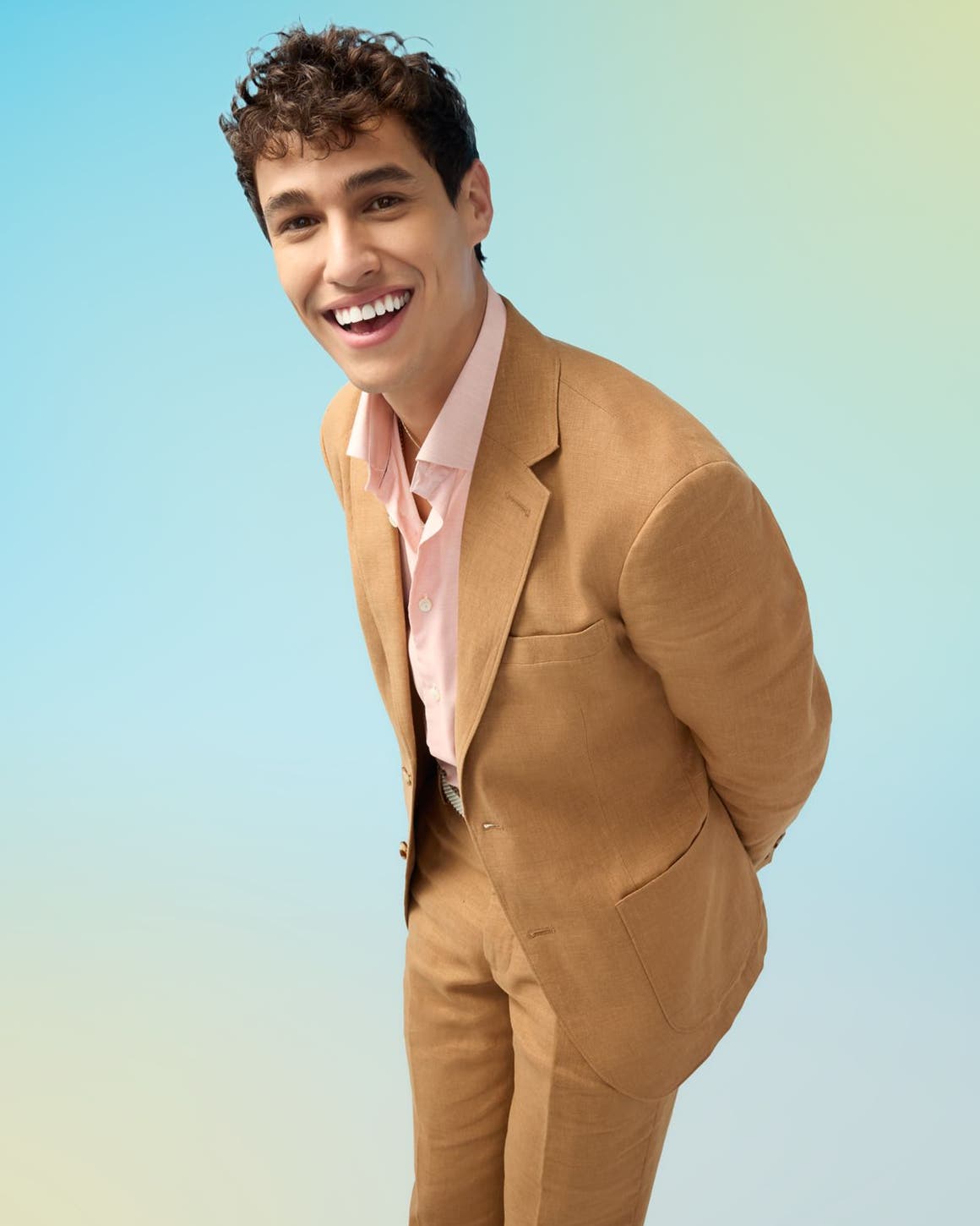 A man in a tan suit and pink shirt.