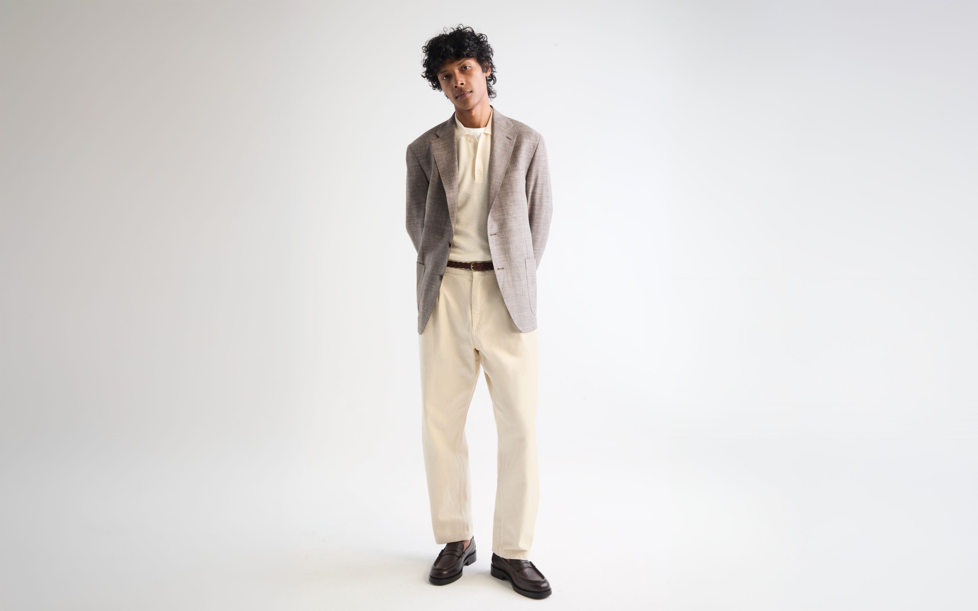 Man wearing a blazer, polo shirt, trousers, belt and loafers.