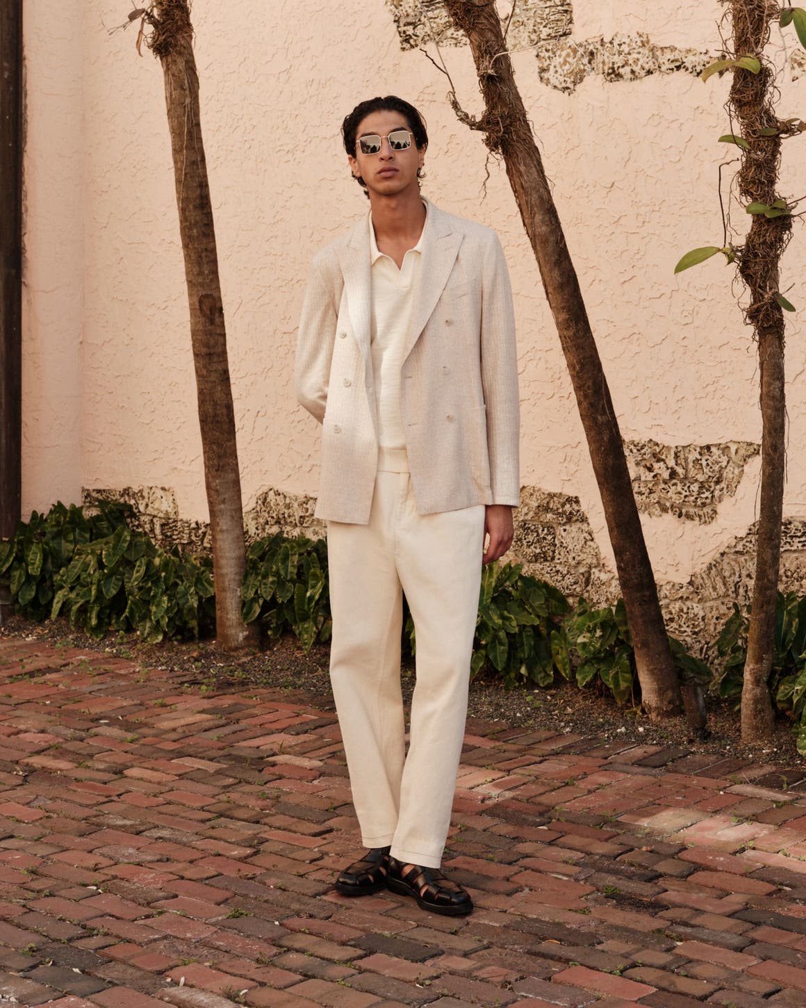 Man wearing a cream double-breasted blazer, wide-leg trousers and fisherman sandals.