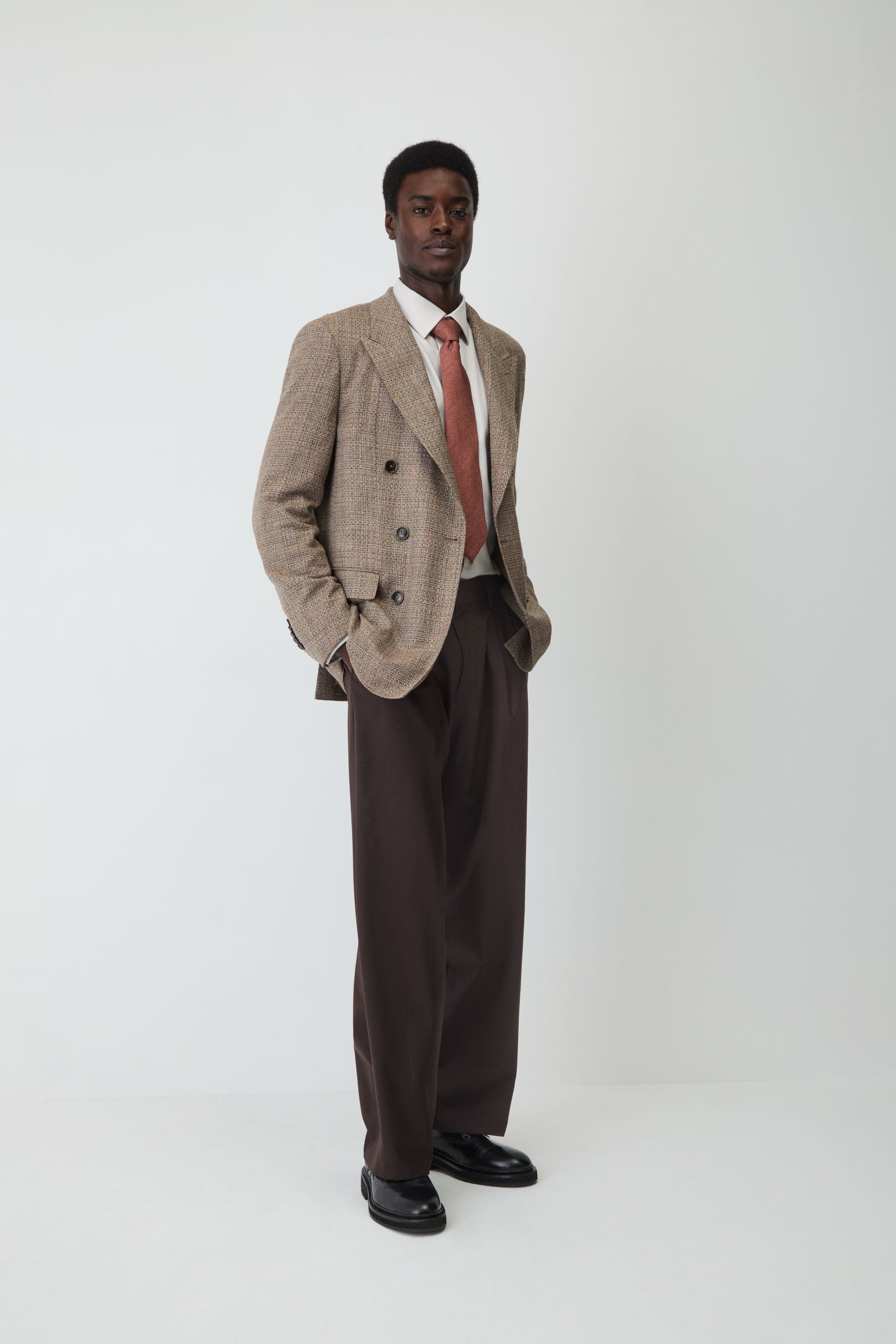A man wearing blazer, dress pants, button up, tie and shoes.
