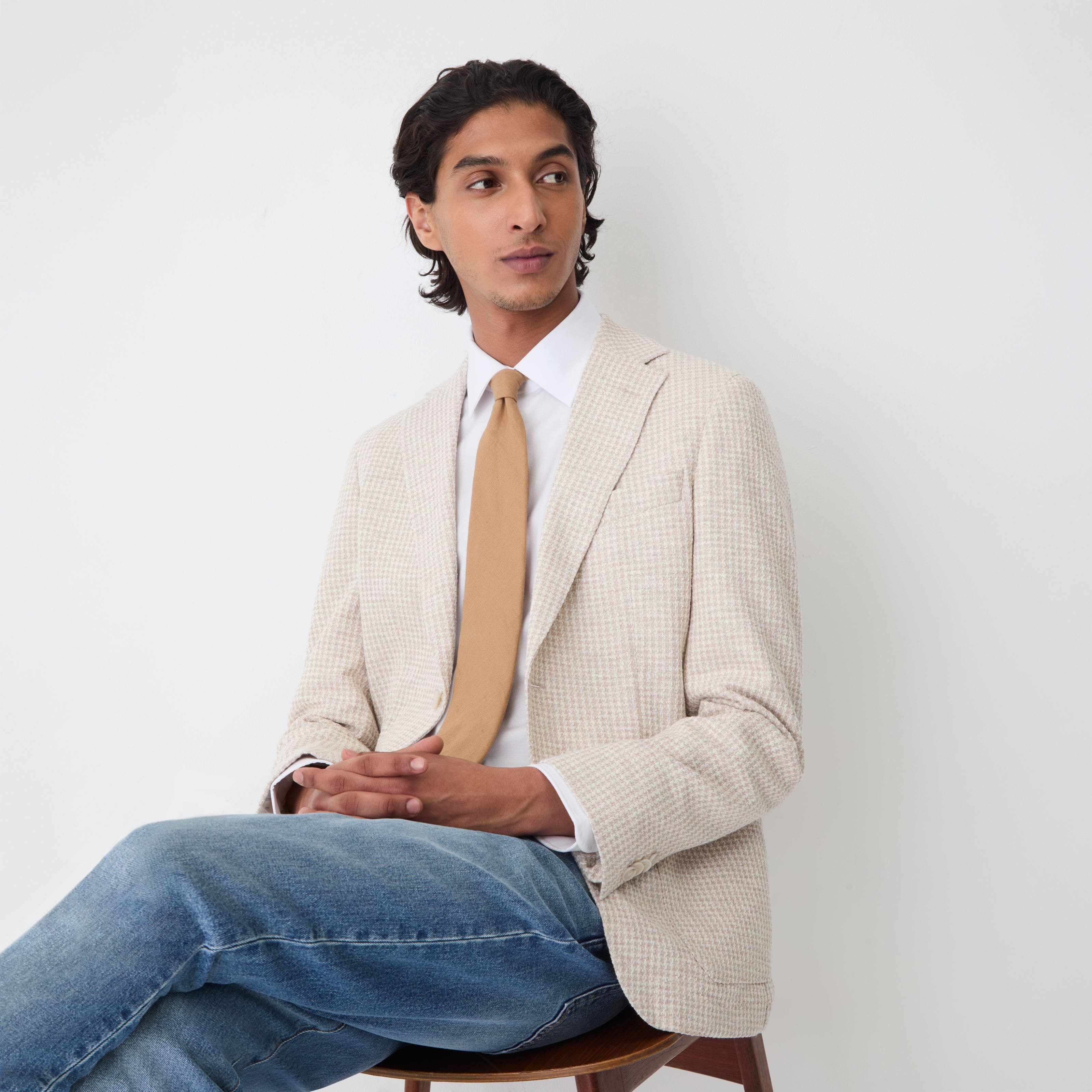 A man wearing sportscoat, dress shirt, tie and denim.