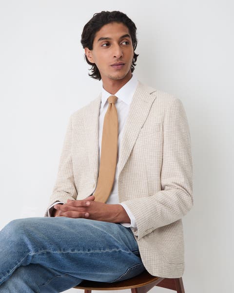 A man wearing sportscoat, dress shirt, tie and denim.