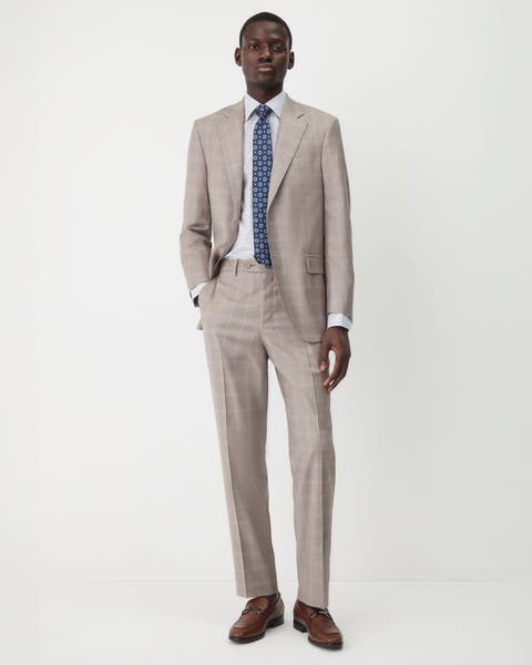 A man wearing a tan suit with a checked shirt and medallion tie.