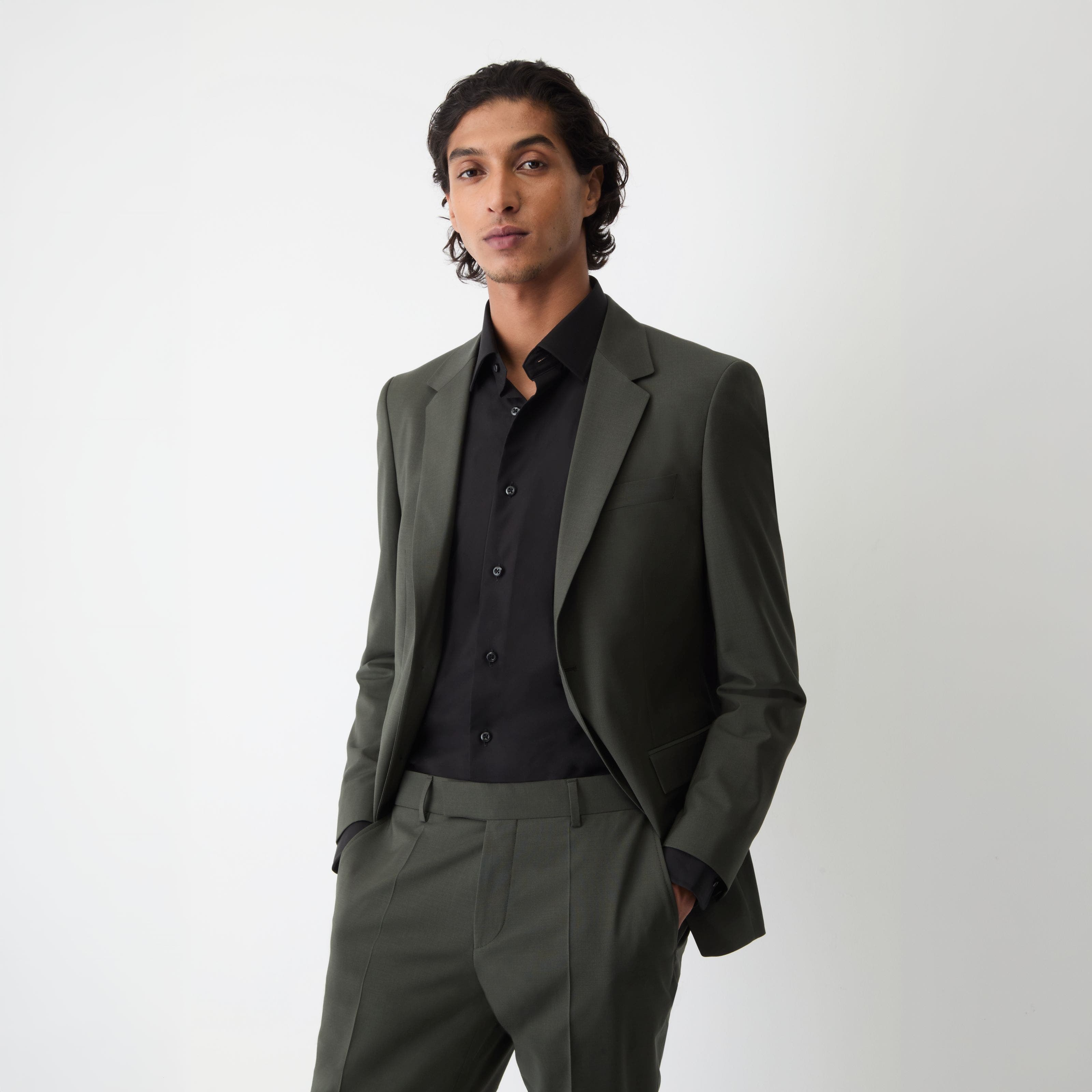 A man wearing grey suit with black dress shirt.