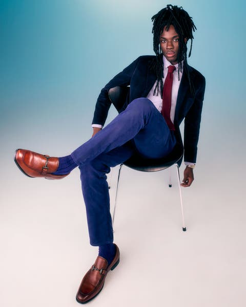 Man wearing a navy suit, a white dress shirt, a red tie and brown shoes.