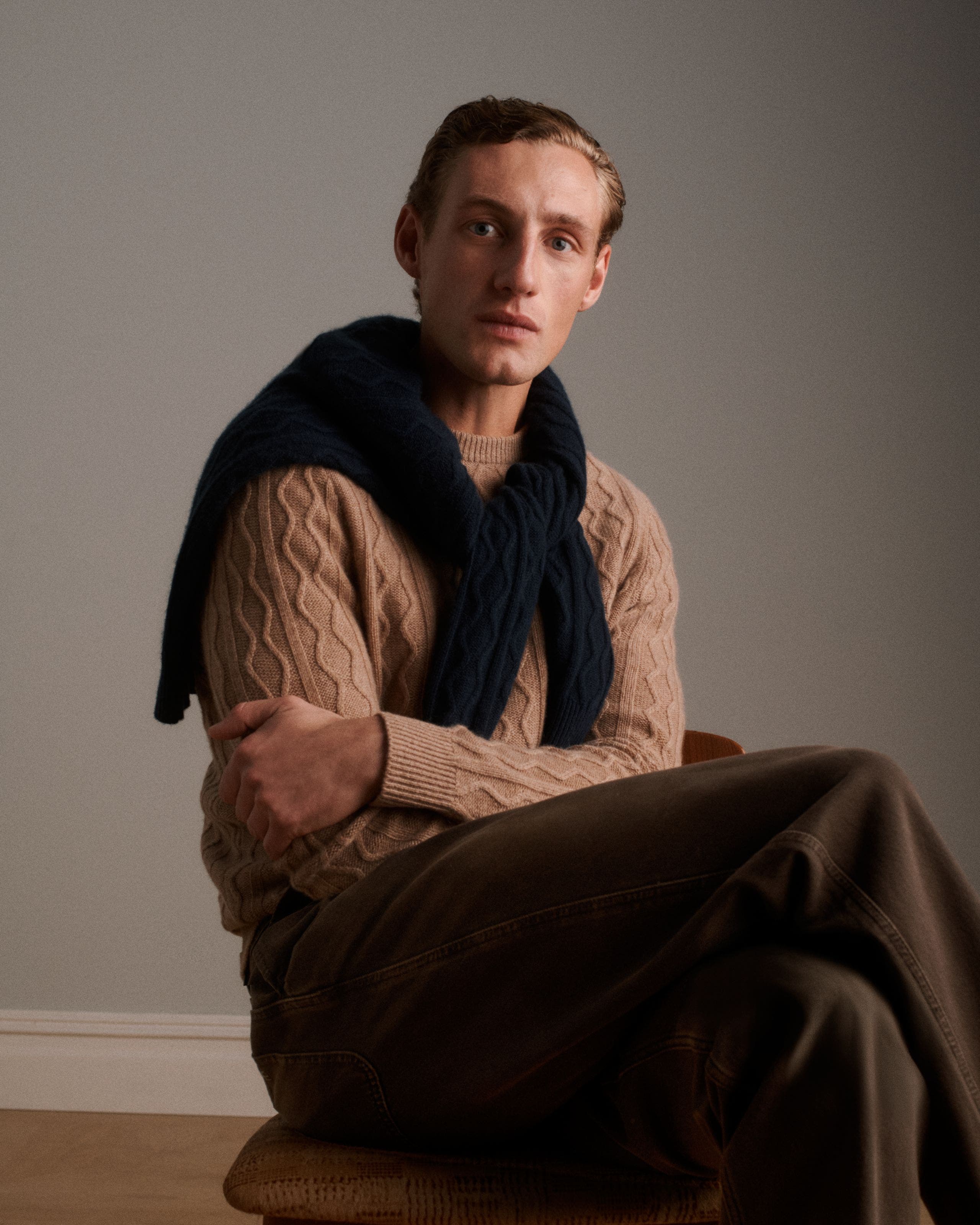 A man wearing a brown sweater and slacks.