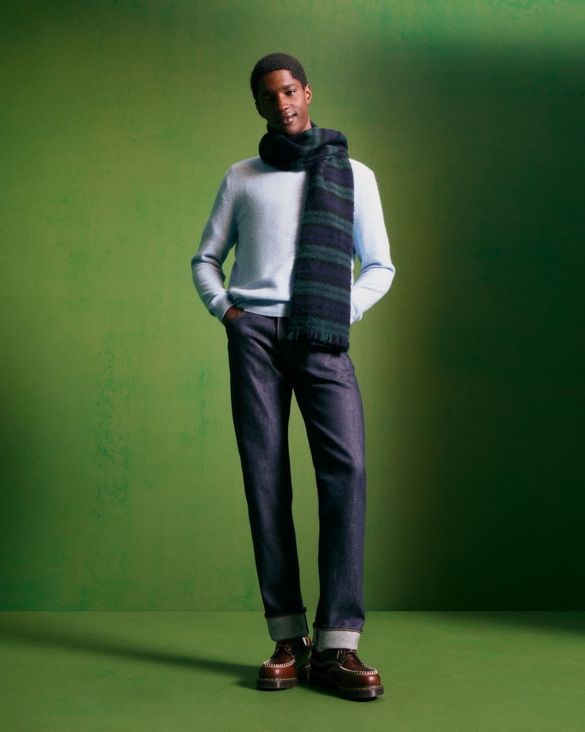 Man wearing a cashmere sweater, scarf, jeans and boots.