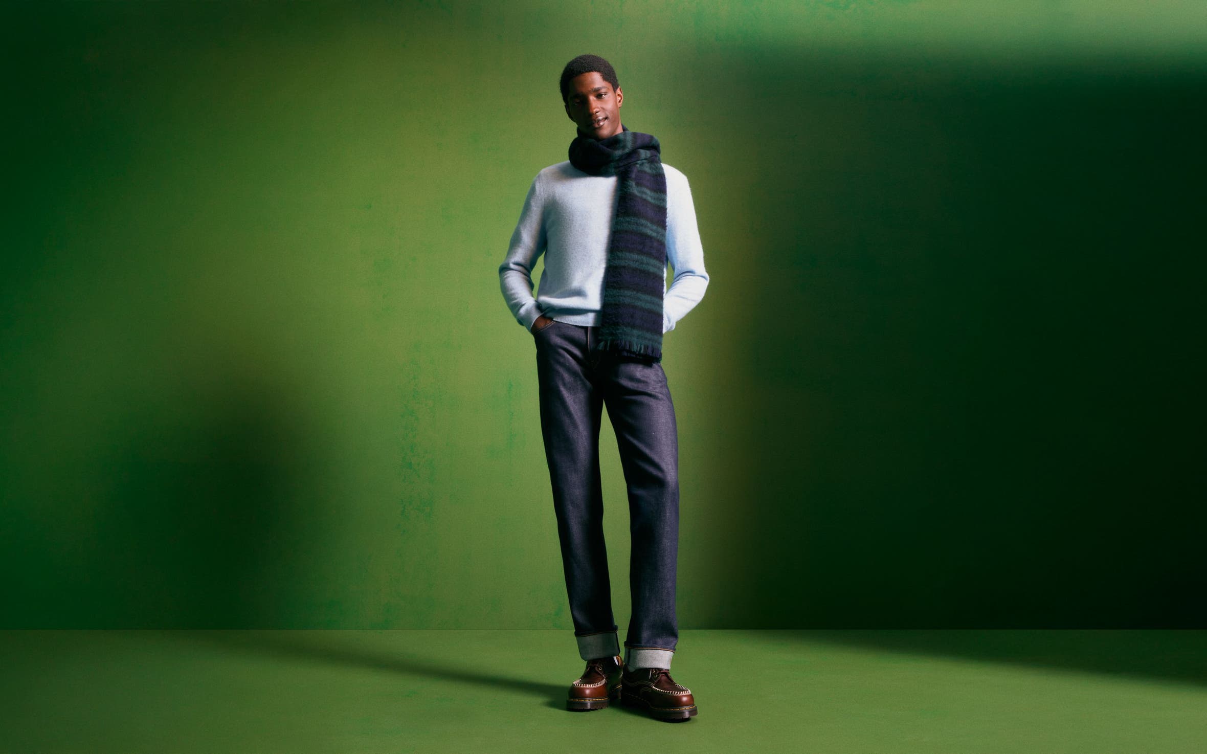 Man wearing a cashmere sweater, scarf, jeans and boots.