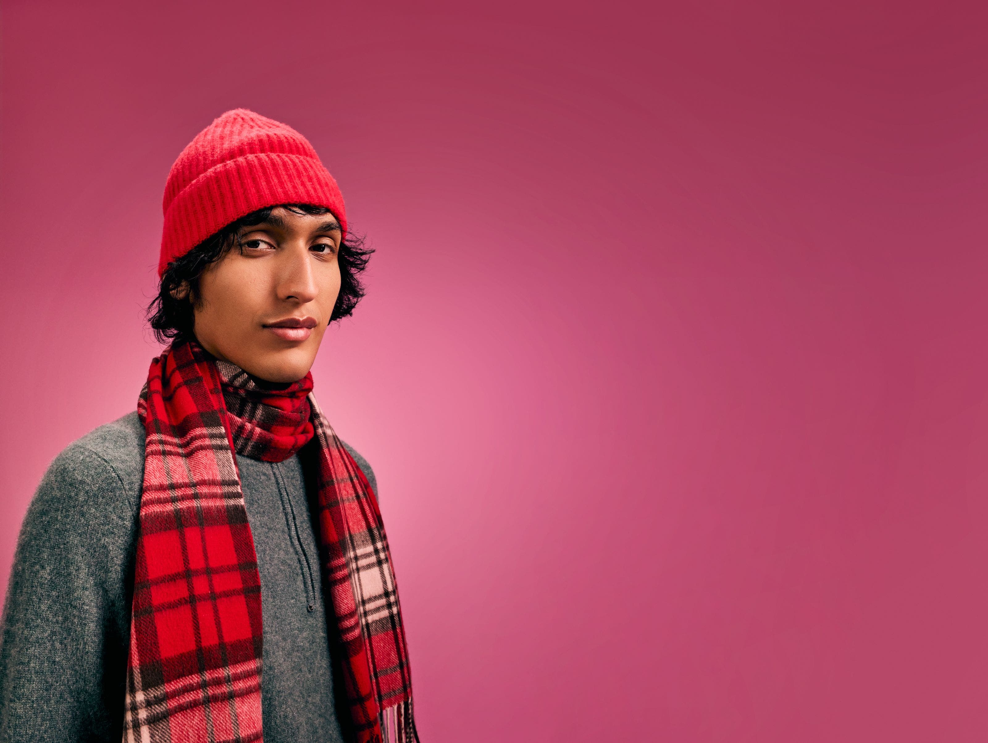 A man wearing a red plaid scarf and red beanie.