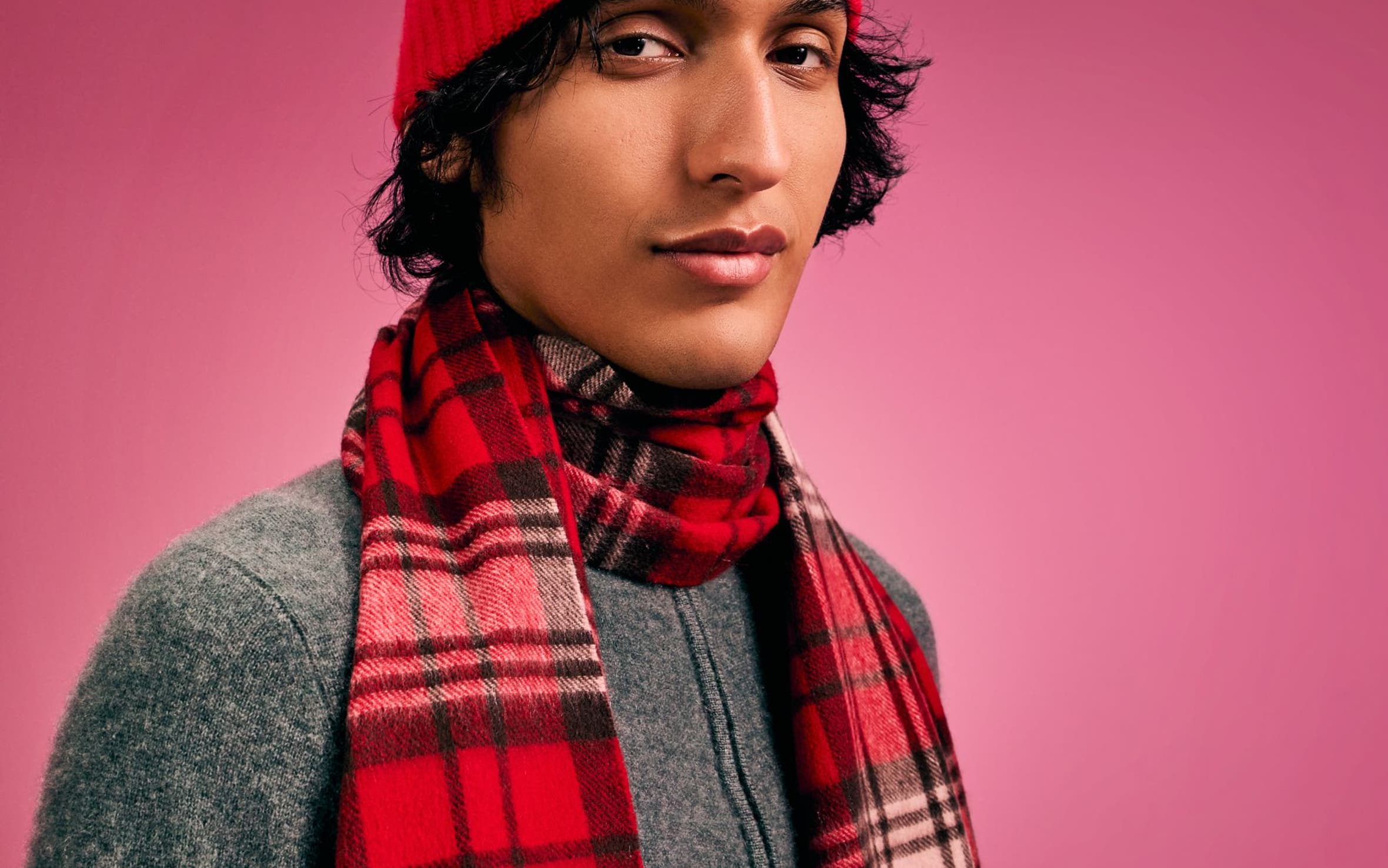 A man wearing a red plaid scarf and red beanie.
