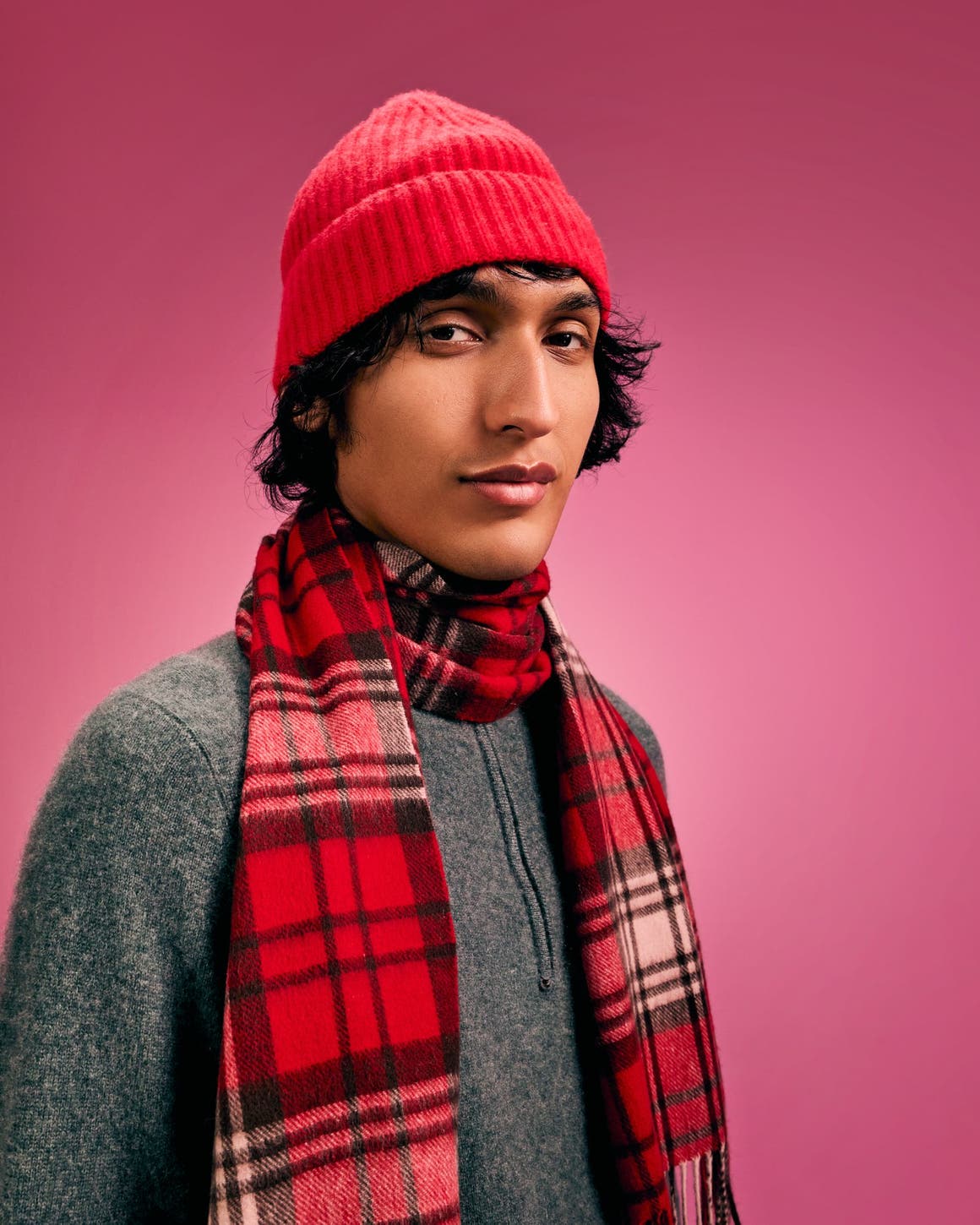 A man wearing a red plaid scarf and red beanie.