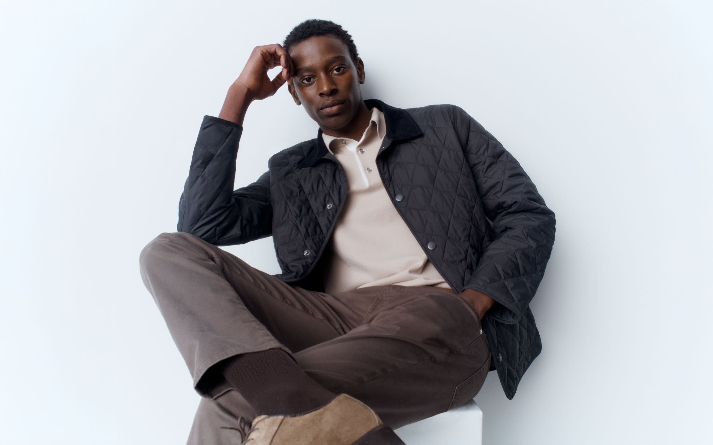 A man wearing a quilted jacket with a polo and pants.