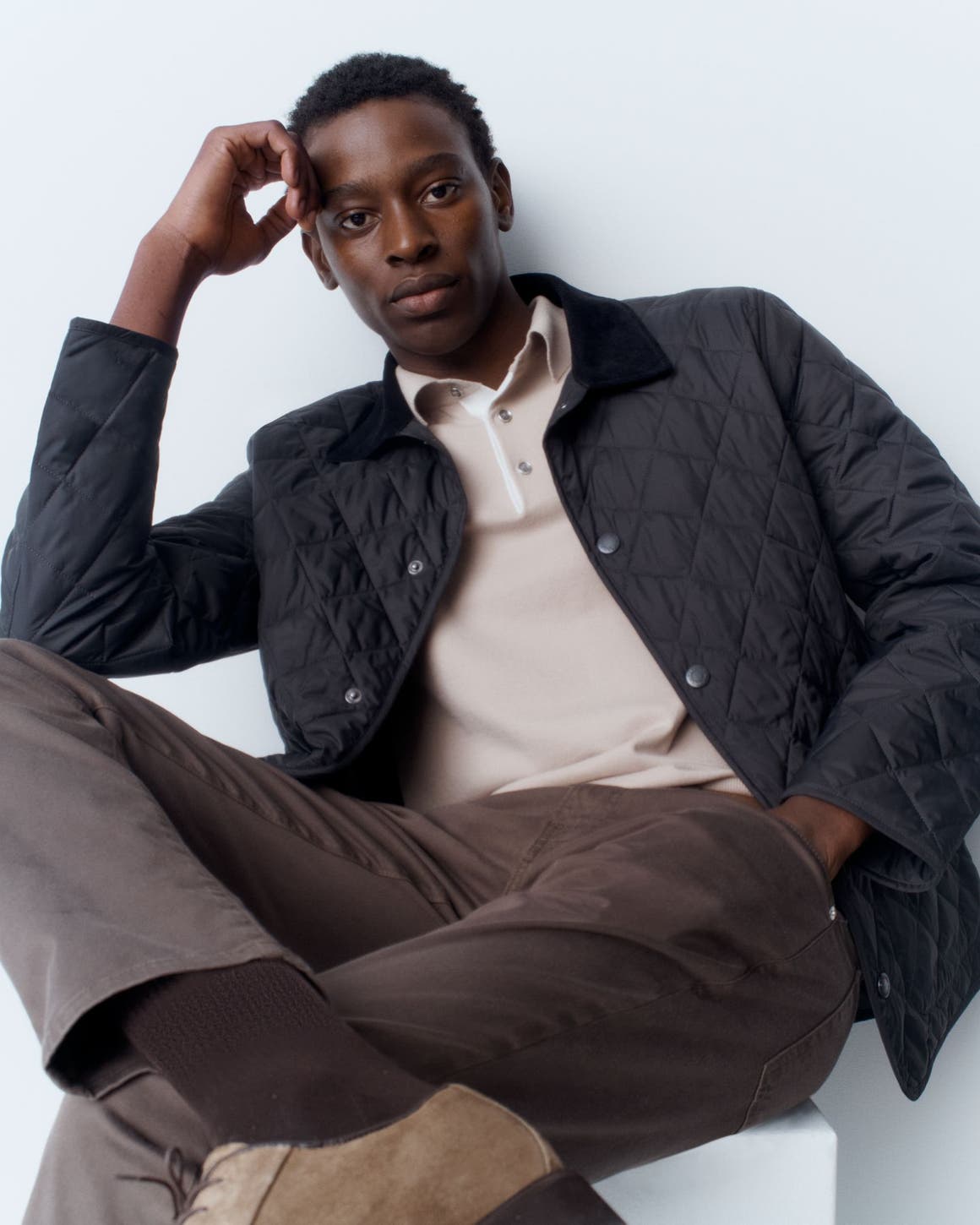 A man wearing a quilted jacket with a polo and pants.