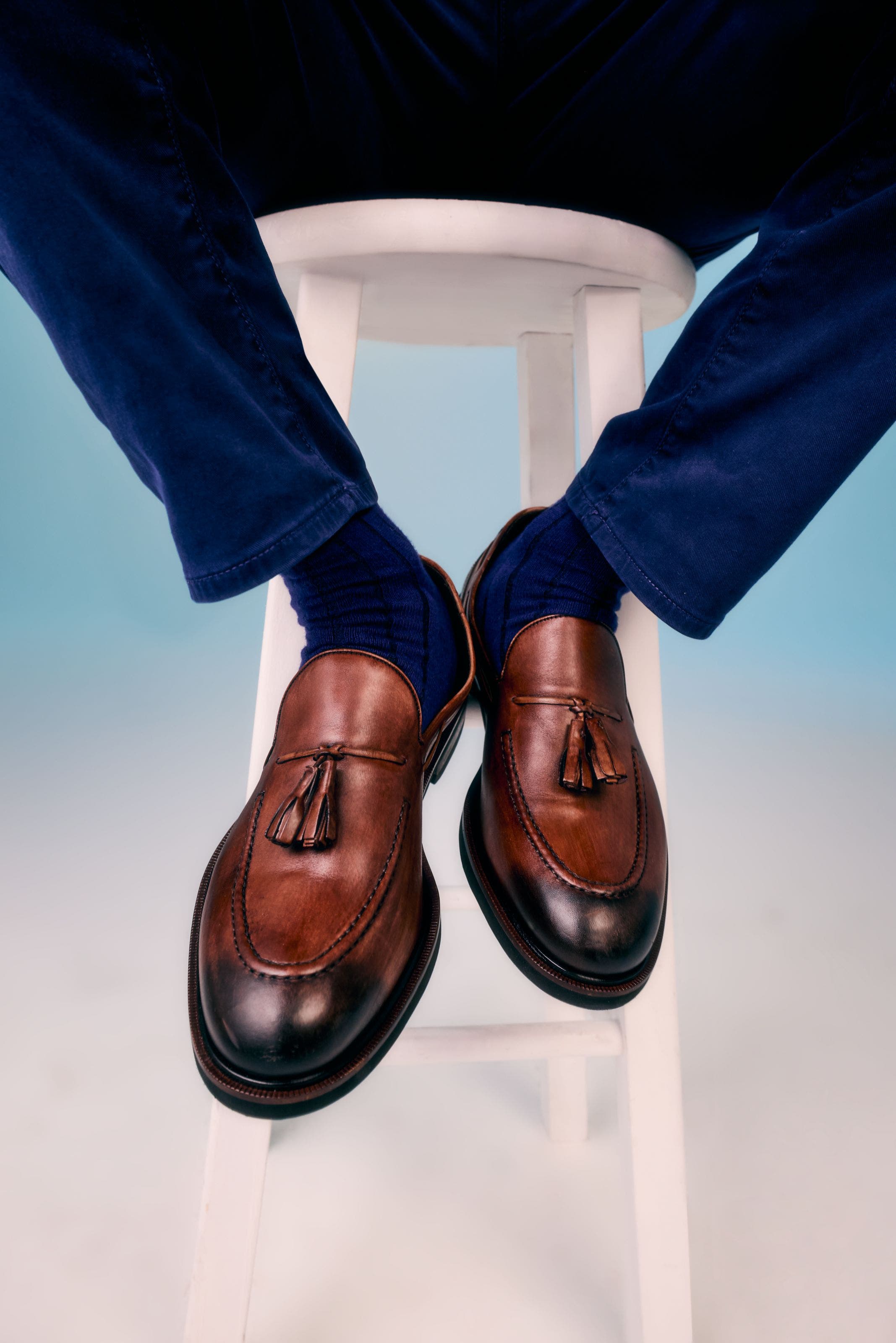 A man wearing brown leather tassel loafers with dark burnished toes.
