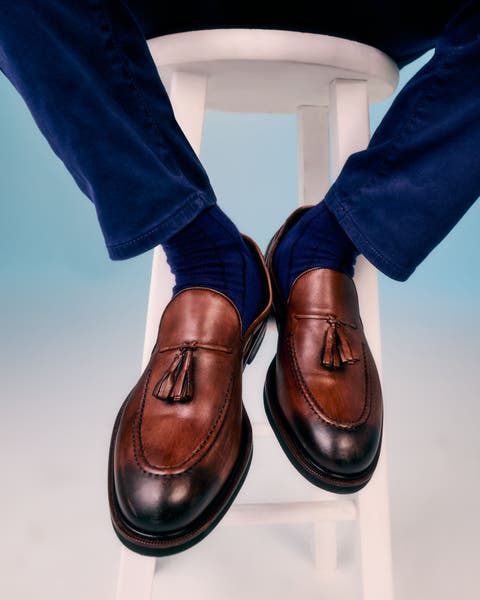 A man wearing brown leather tassel loafers with dark burnished toes.