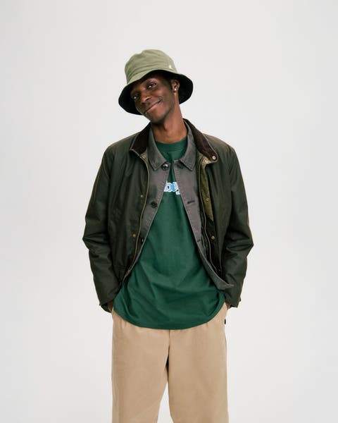 Man wearing two jackets, a graphic T-shirt, baggy chinos and a bucket hat.