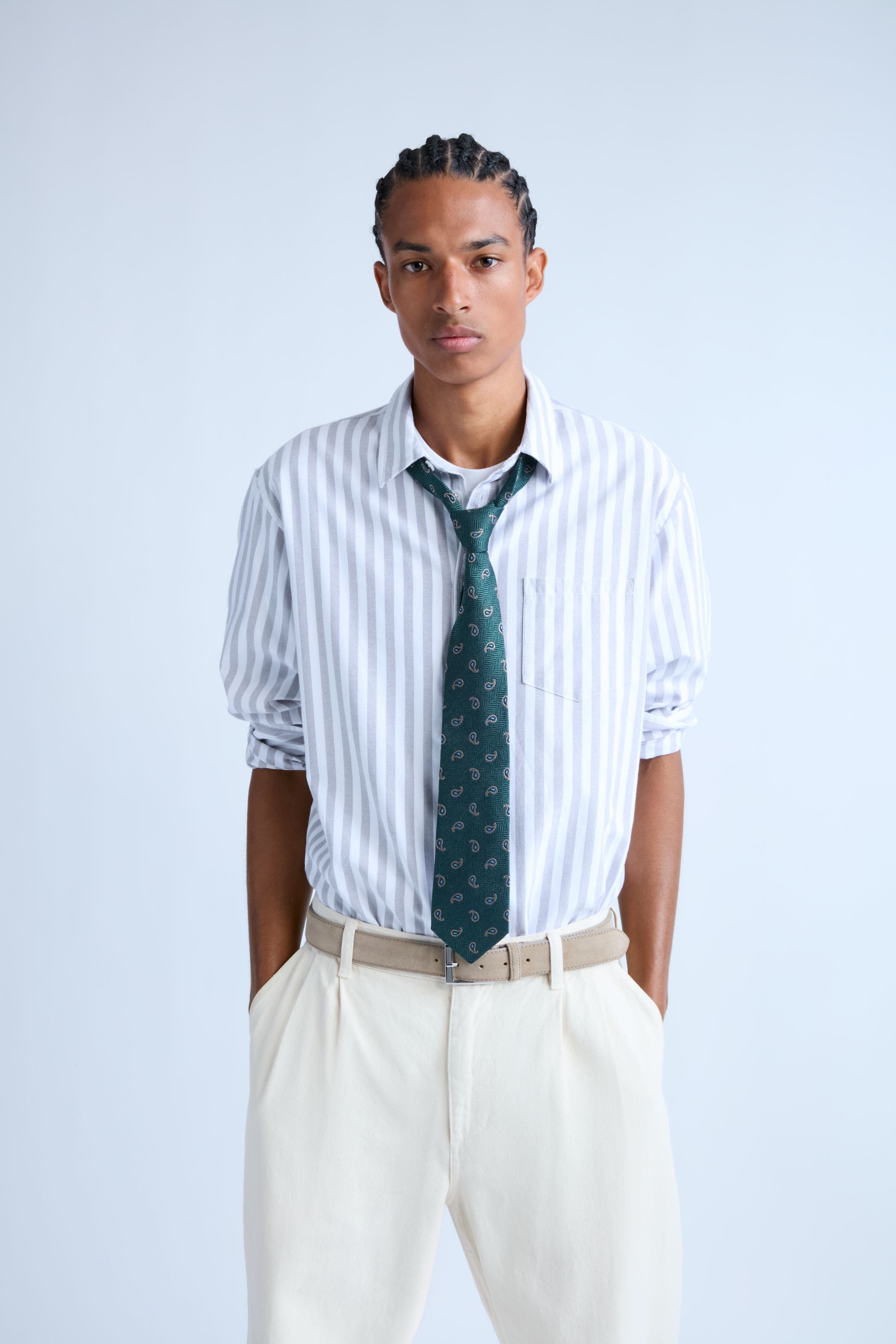 Man wearing a striped shirt with a green tie.