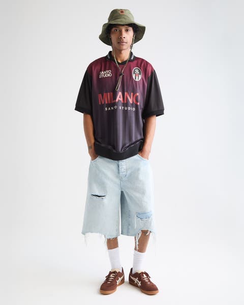 Man wearing Santo Studio jersey and denim shorts.