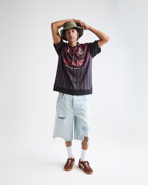 A man wearing a graphic T-shirt and baggy shorts.