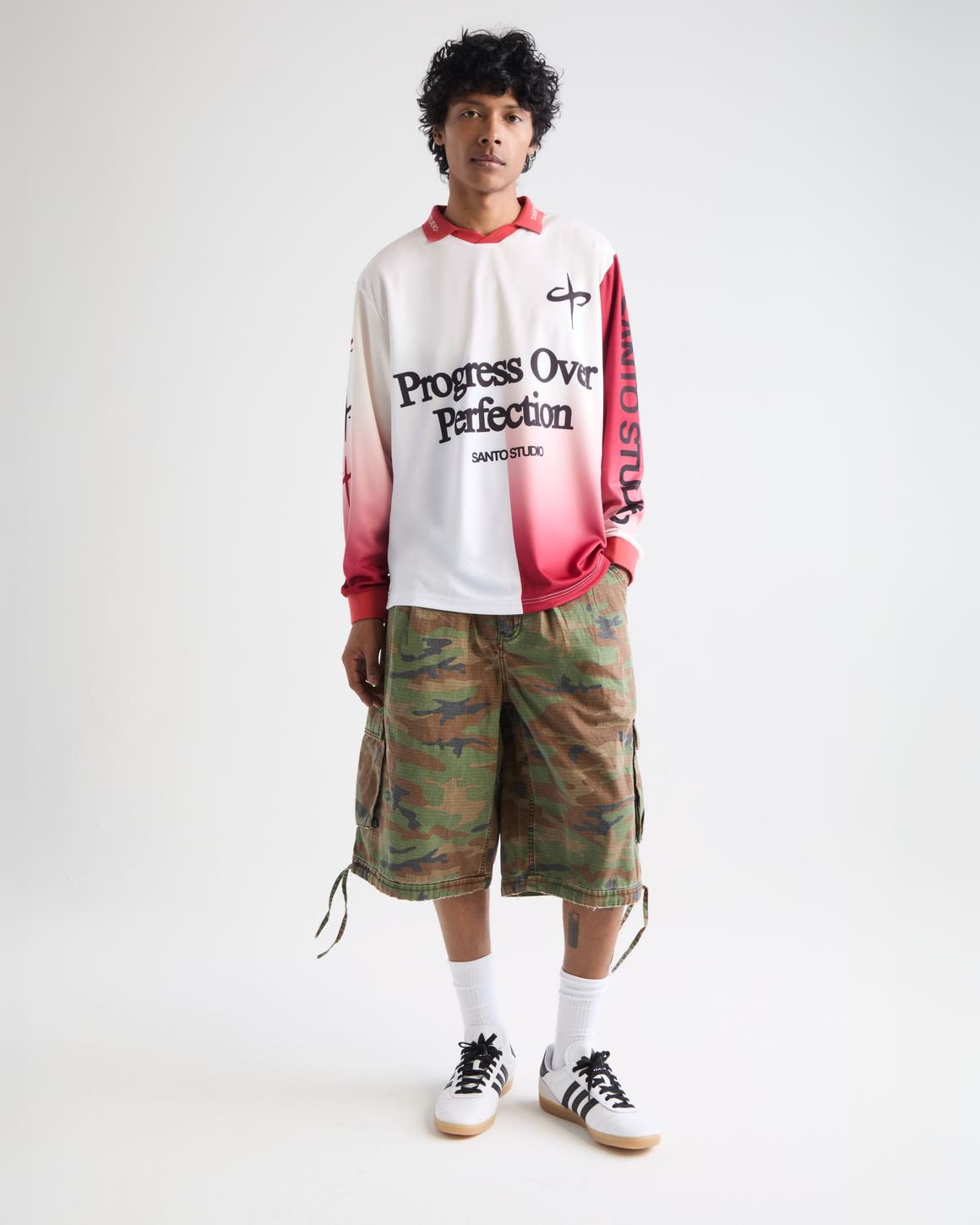 Man wearing a long-sleeve jersey, camo shorts and sneakers.