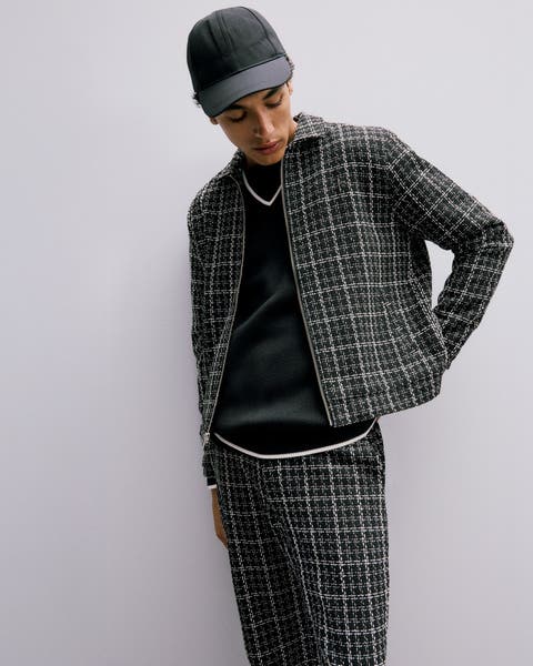 Man wearing matching printed jacket and pants, a sweater and cap.