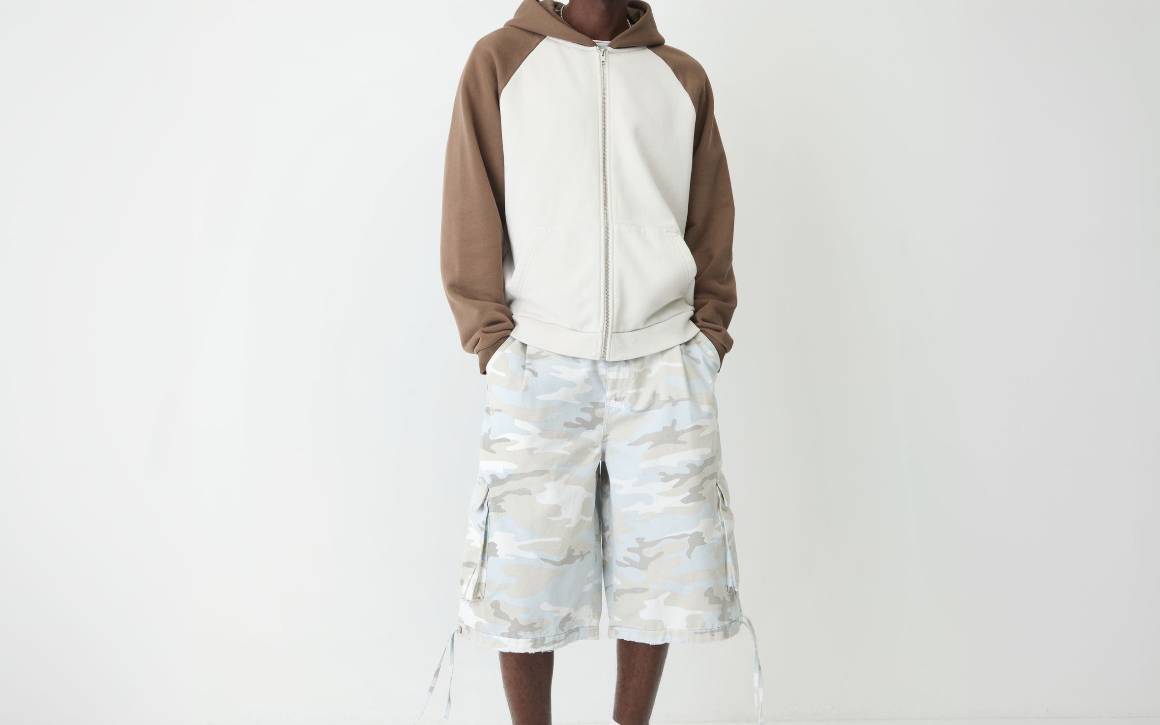 A man in tonal camo-print shorts, a color-block sweatshirt and suede slip-ons.
