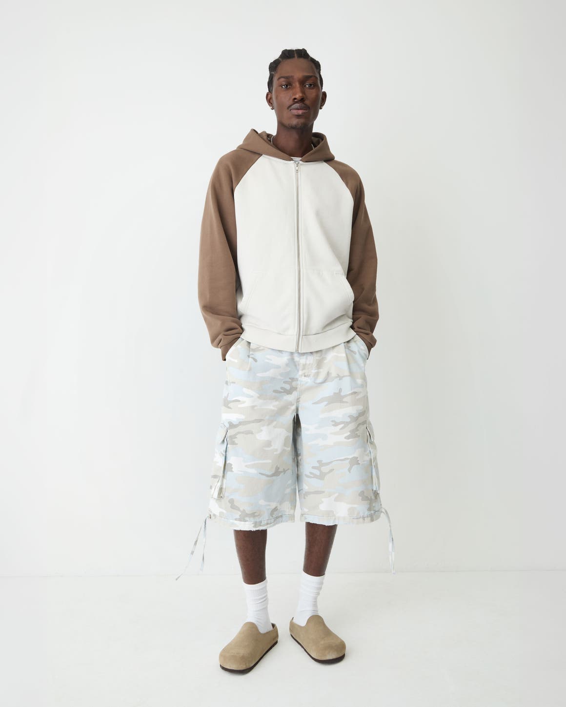 A man in tonal camo-print shorts, a color-block sweatshirt and suede slip-ons.