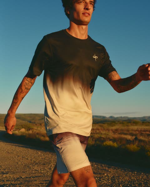 A man wearing a color-fade T-shirt and shorts while walking.