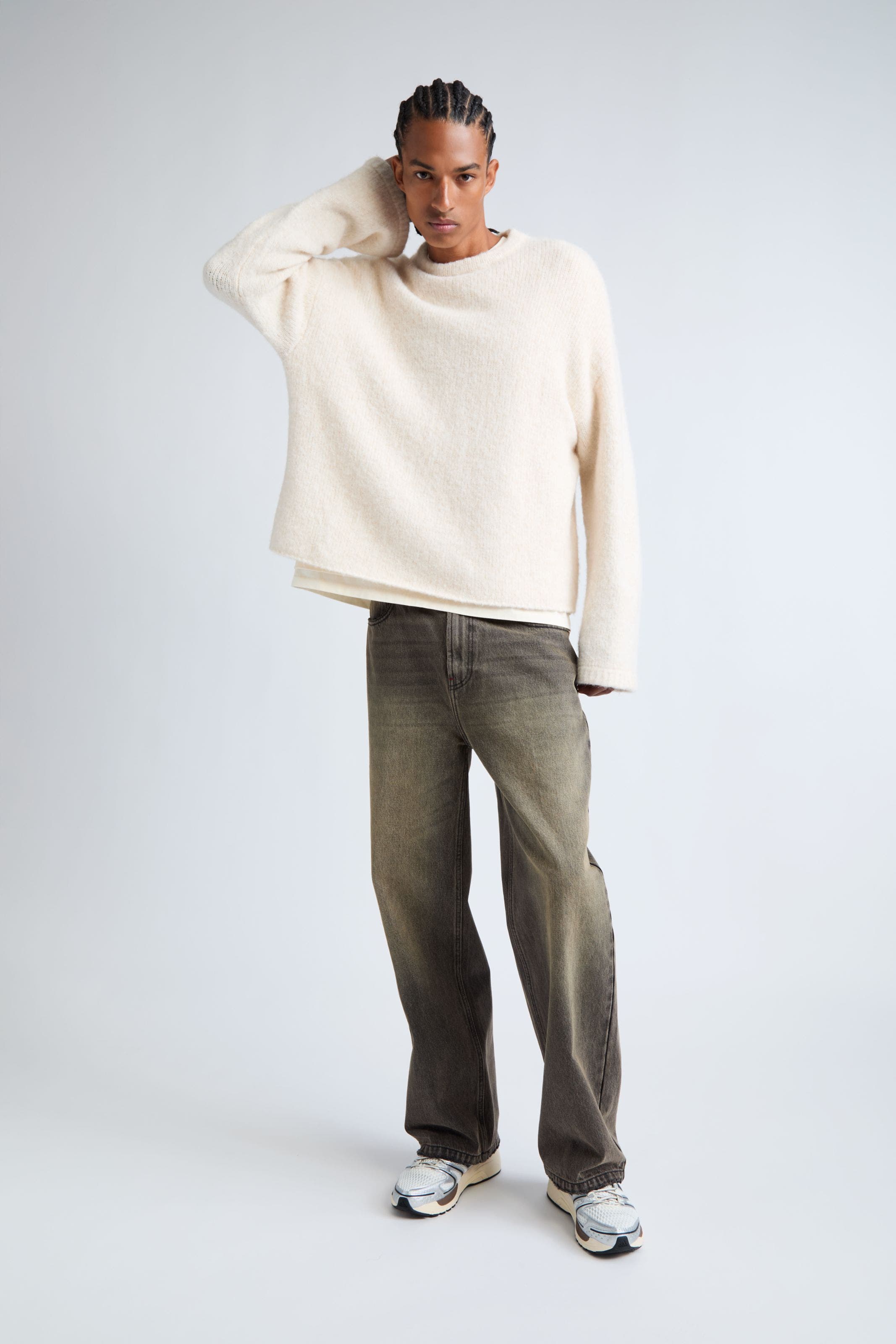 A man wearing a sweater, jeans and sneakers.