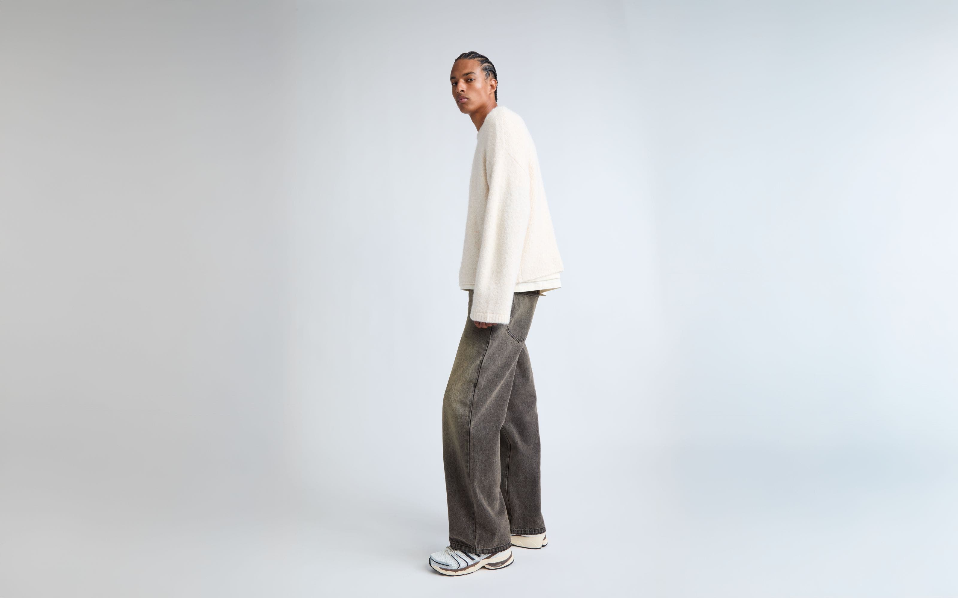 A man wearing baggy, faded grey jeans.