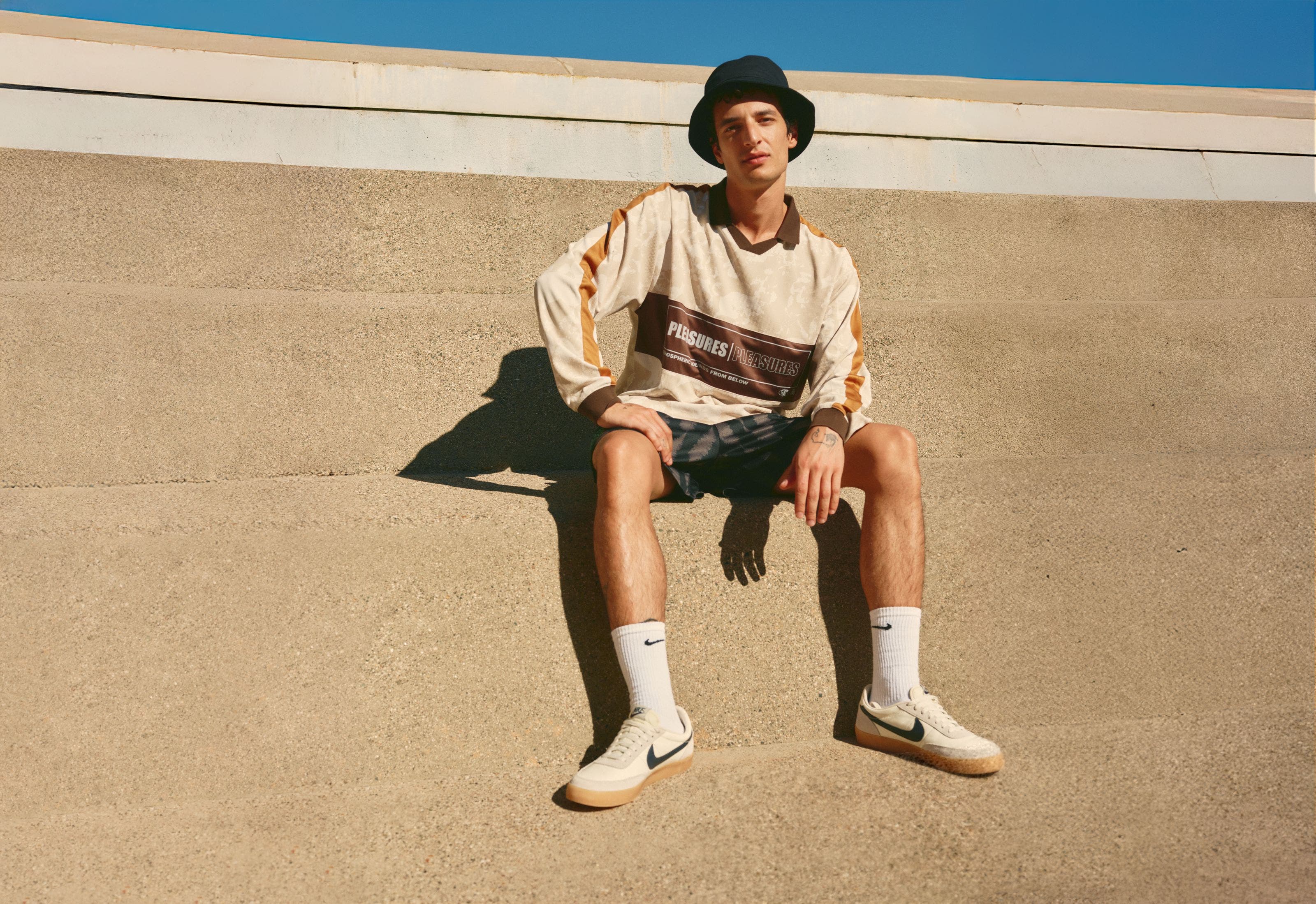 Man wearing a long-sleeve polo shirt, shorts, bucket hat and sneakers.