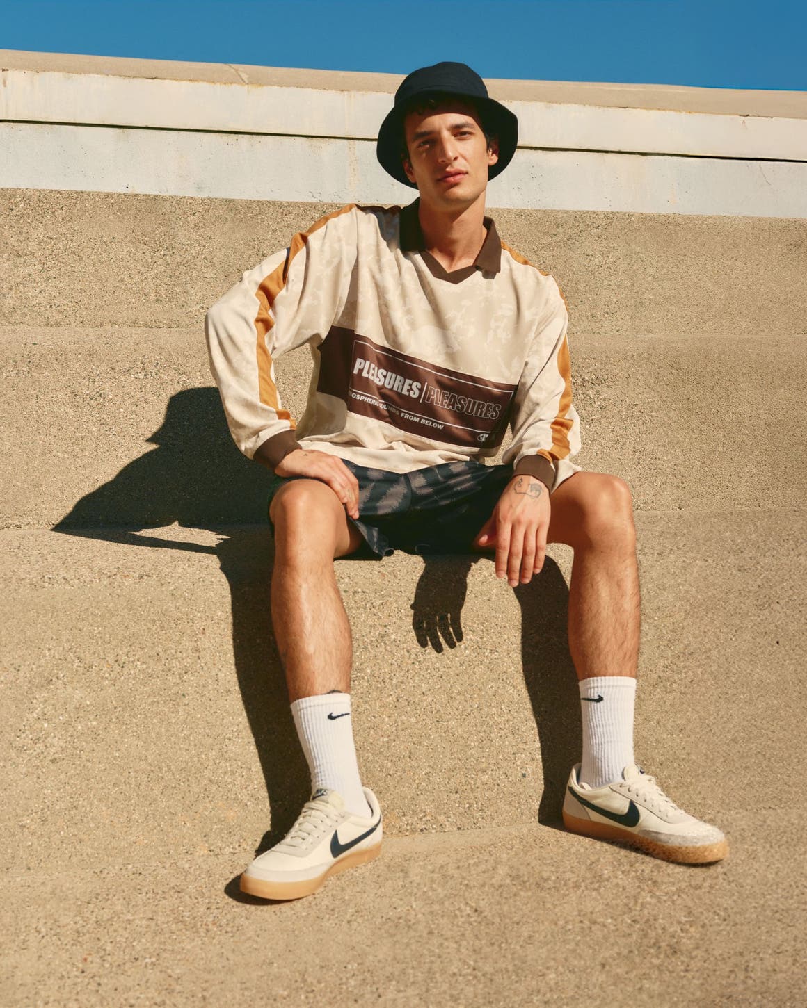  Man wearing a bucket hat, long-sleeve polo shirt, shorts, socks and sneakers.