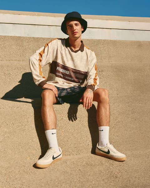 Man wearing a long-sleeve polo, shorts, bucket hat and sneakers.