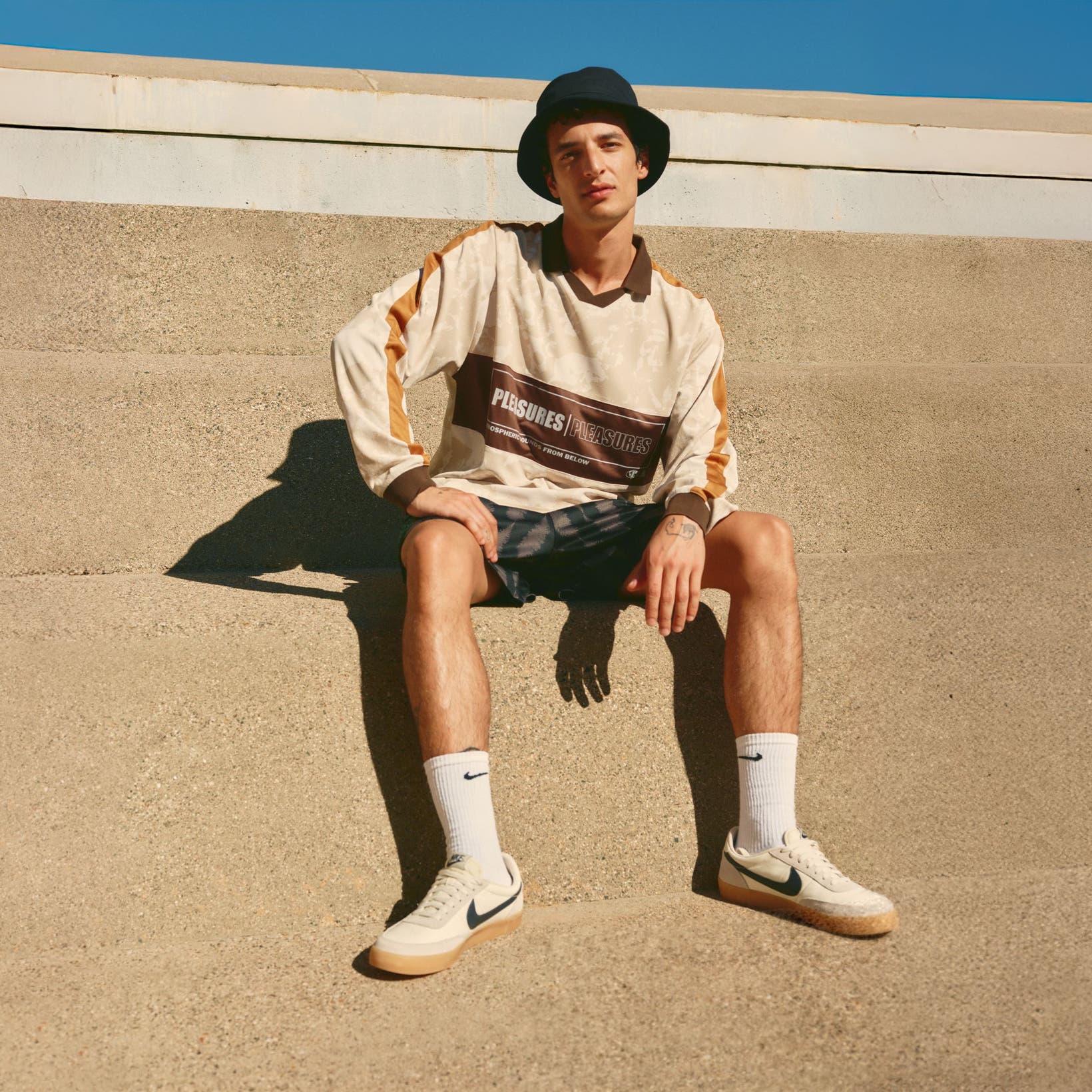  Man wearing a bucket hat, long-sleeve polo shirt, shorts, socks and sneakers.