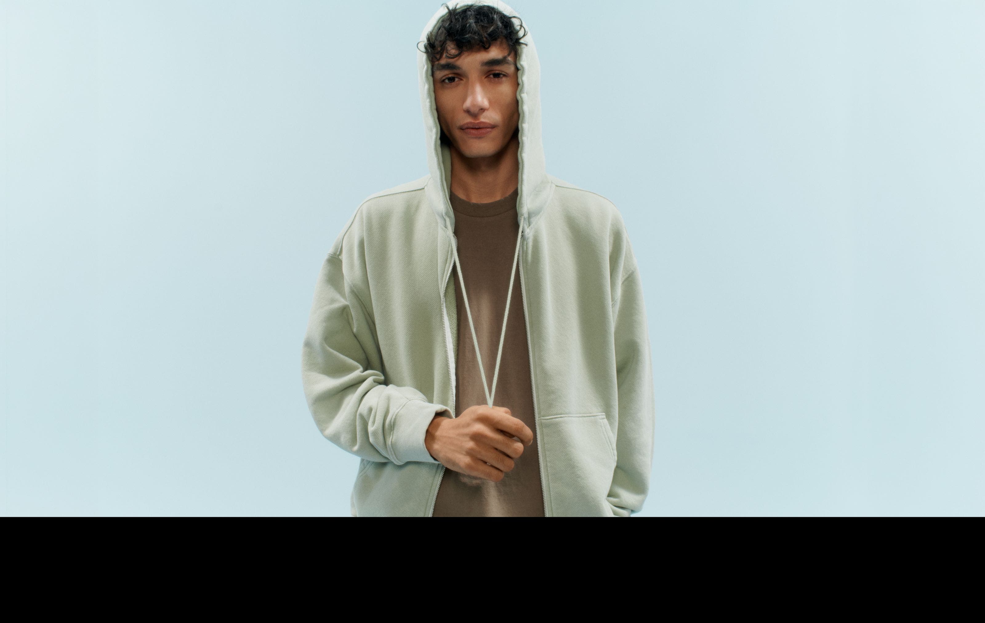 A man in a green hoodie and brown tee.
