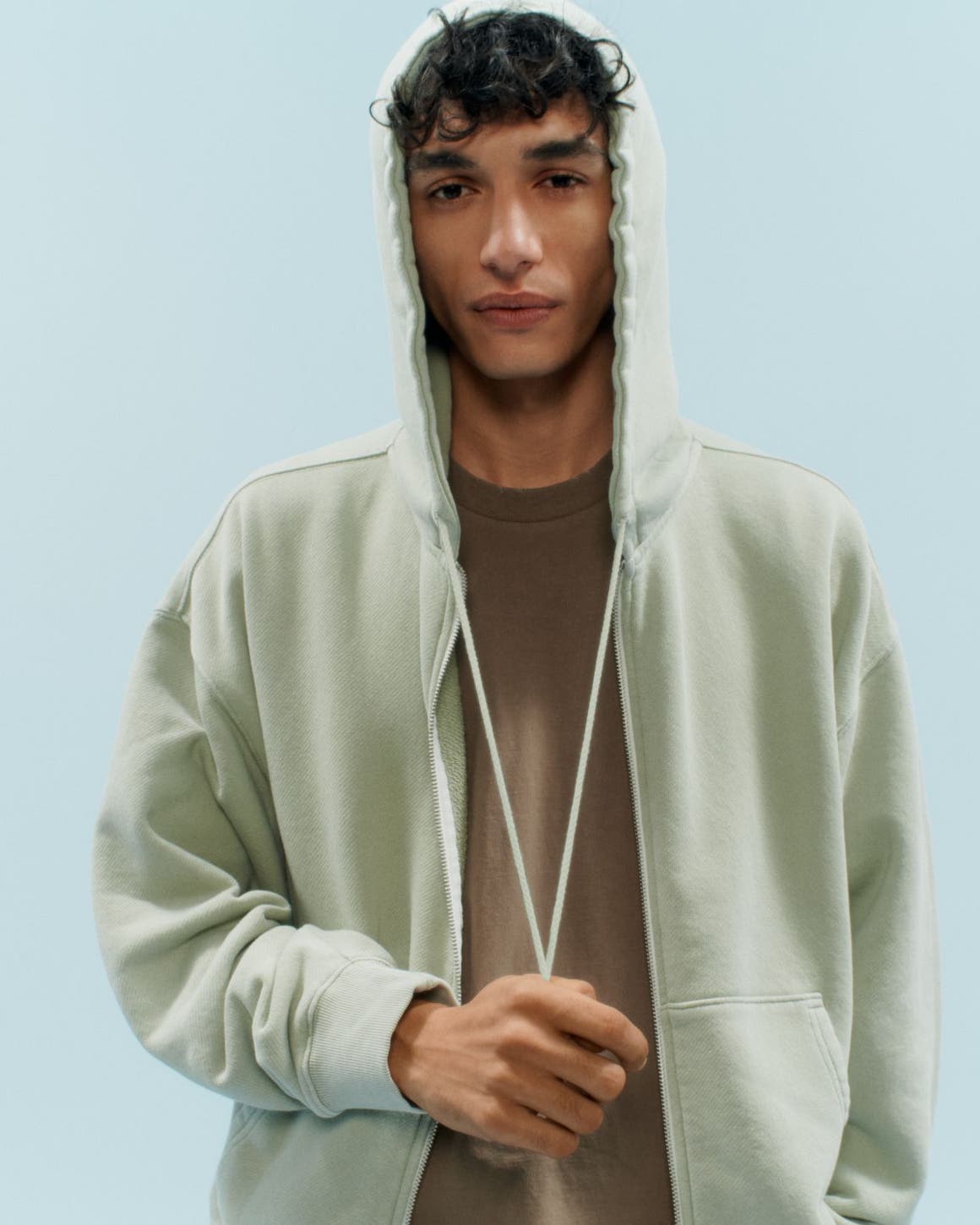 A man in a green hoodie and brown tee.