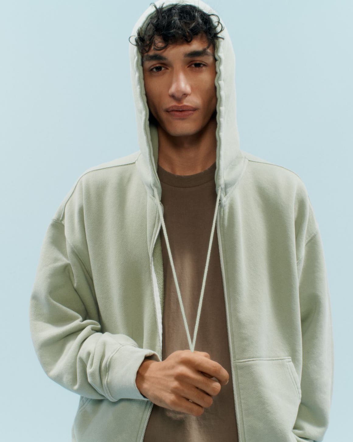 A man in a green hoodie and brown tee.