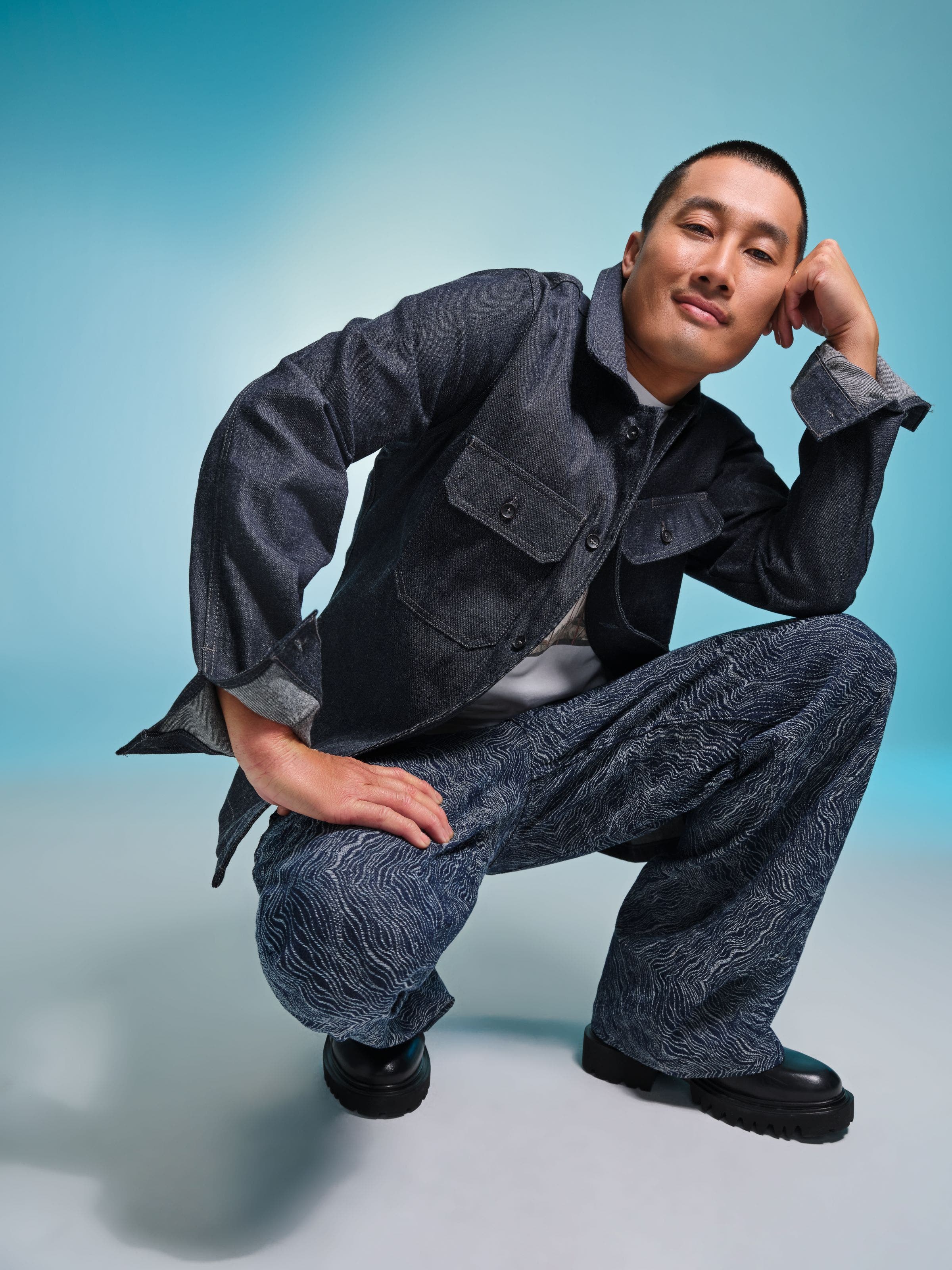 Man wearing a gray jacket and patterned wide‑leg pants.
