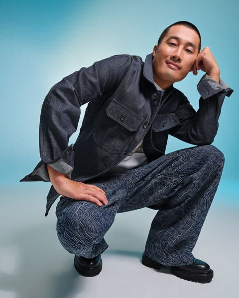 Man wearing a gray jacket and patterned wide‑leg pants.