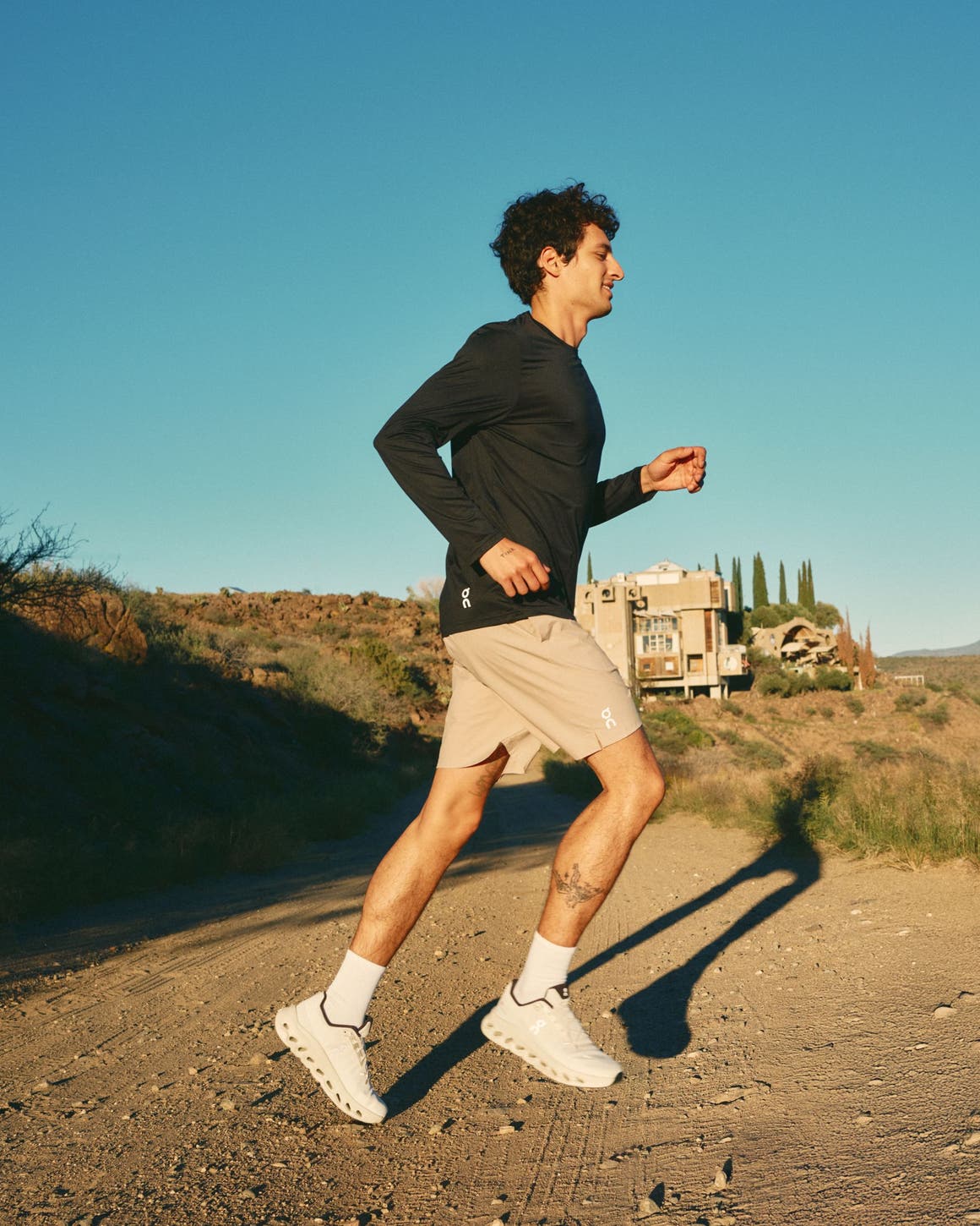 Man wearing a black active top, tan shorts and sneakers.