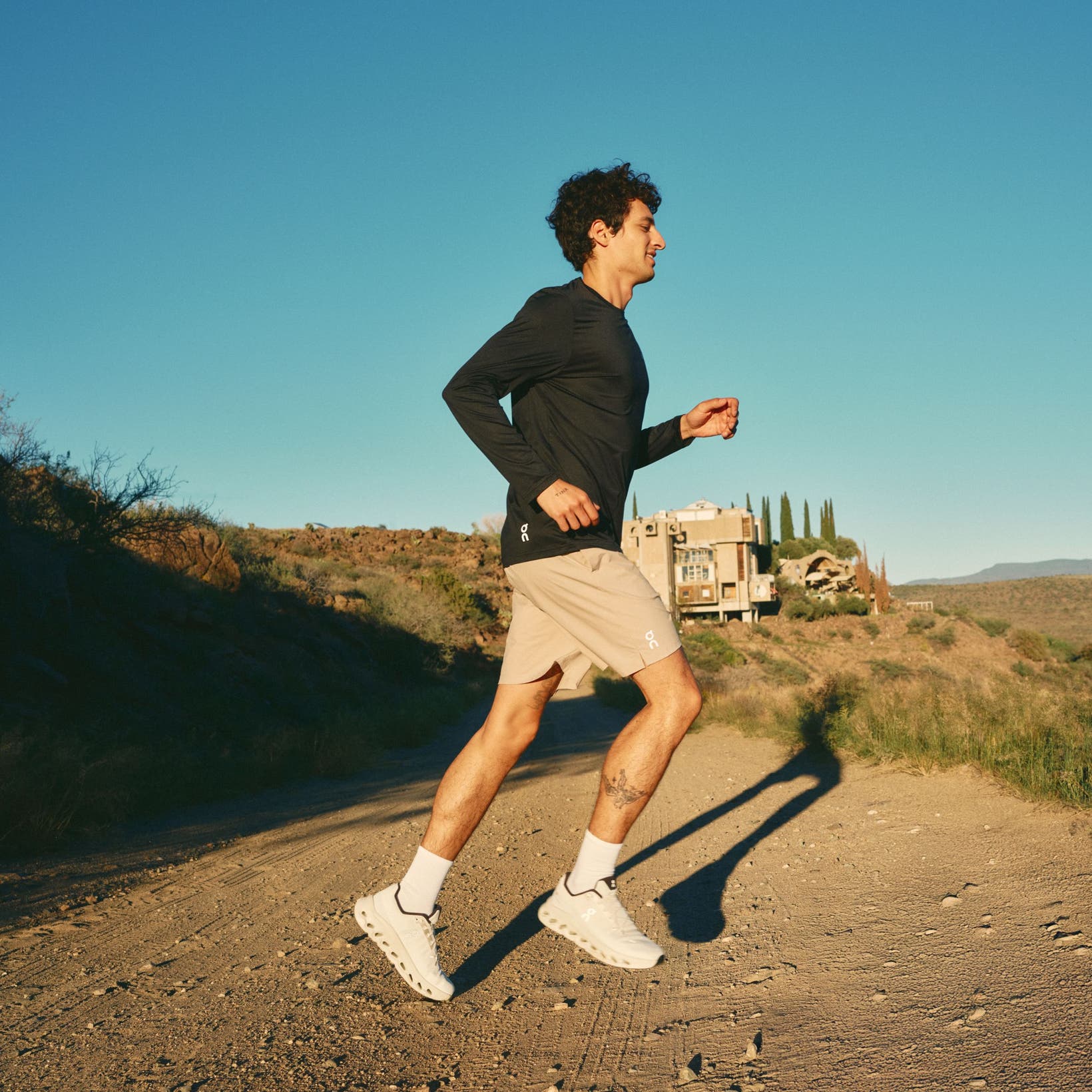 Man wearing a black active top, tan shorts and sneakers.