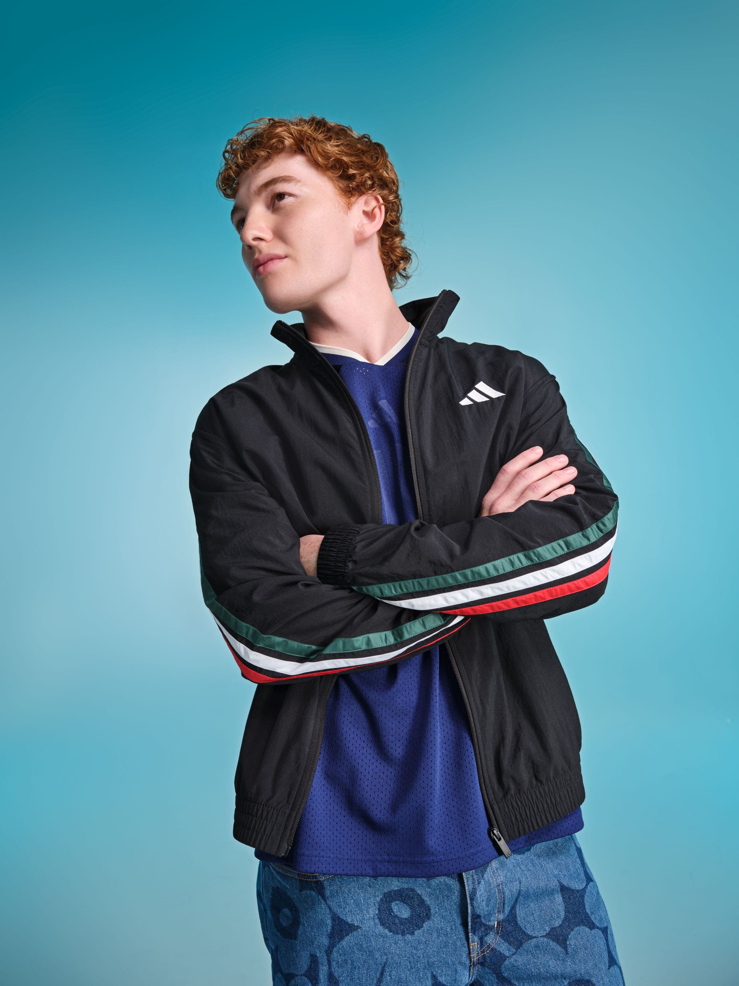 Male model wearing a black Adidas track jacket with multicolor stripe sleeve detail.