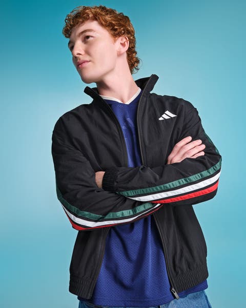 Male model wearing a black Adidas track jacket with multicolor stripe sleeve detail.